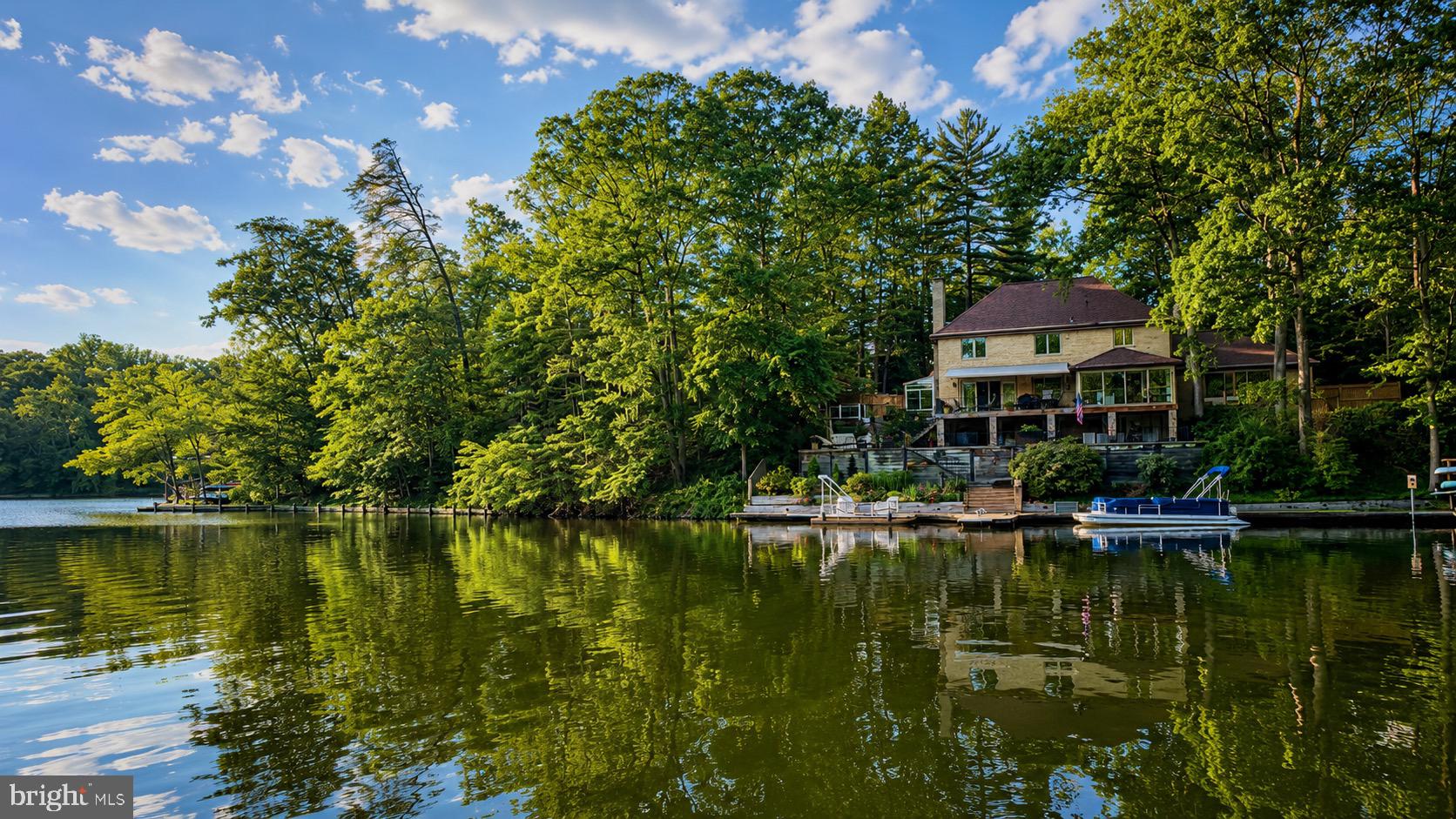 European Elegance, Waterfront Serenity, Just Minutes from Washington, DC.
Tucked away at the end of a quiet cul-de-sac, this waterfront estate feels more like a private European lakeside retreat than a home just eight miles from Washington, DC.<br><br>Surrounded by mature hardwoods and overlooking the tranquil waters of Lake Barcroft, the residence blends the elegance of a European manor with the serenity of lakeside living. Its stately brick façade, dramatic rooflines, wrought-iron balcony, and gated approach create a memorable arrival, while the rear of the home reveals an extraordinary waterfront setting where expansive terraces, decks, and entertaining spaces descend gracefully toward the shoreline.<br><br>Inside, lake views fill nearly every room, creating a seamless connection to the natural beauty beyond. Whether enjoying morning coffee overlooking the water, hosting sunset gatherings on the terrace, soaking in the lakeside hot tub beneath the stars, or launching a kayak from your private dock, every day feels like a getaway.<br><br>The private dock offers space for a pontoon boat as well as kayaks and canoes, while the property's carefully crafted stonework, mature landscaping, and peaceful wooded backdrop create a setting that is both sophisticated and remarkably private. From the multi-level terraces overlooking the lake to the inviting outdoor living spaces designed for entertaining and relaxation, the home embraces the very best of waterfront living.<br><br>Equally impressive is the level of care and investment the home has received. The current owners have completed substantial improvements, including a custom kitchen renovation featuring premium cabinetry, appliances, and Italian fixtures; renovated baths; replacement windows and doors; beautiful wood flooring; a light-filled conservatory addition; extensive hardscaping and waterfront stonework; and numerous infrastructure and system upgrades. A complete list of updates is available upon request.<br><br>Just minutes from the heart of Washington, DC, yet worlds away in atmosphere, this is a rare opportunity to experience one of Lake Barcroft's most compelling waterfront offerings.