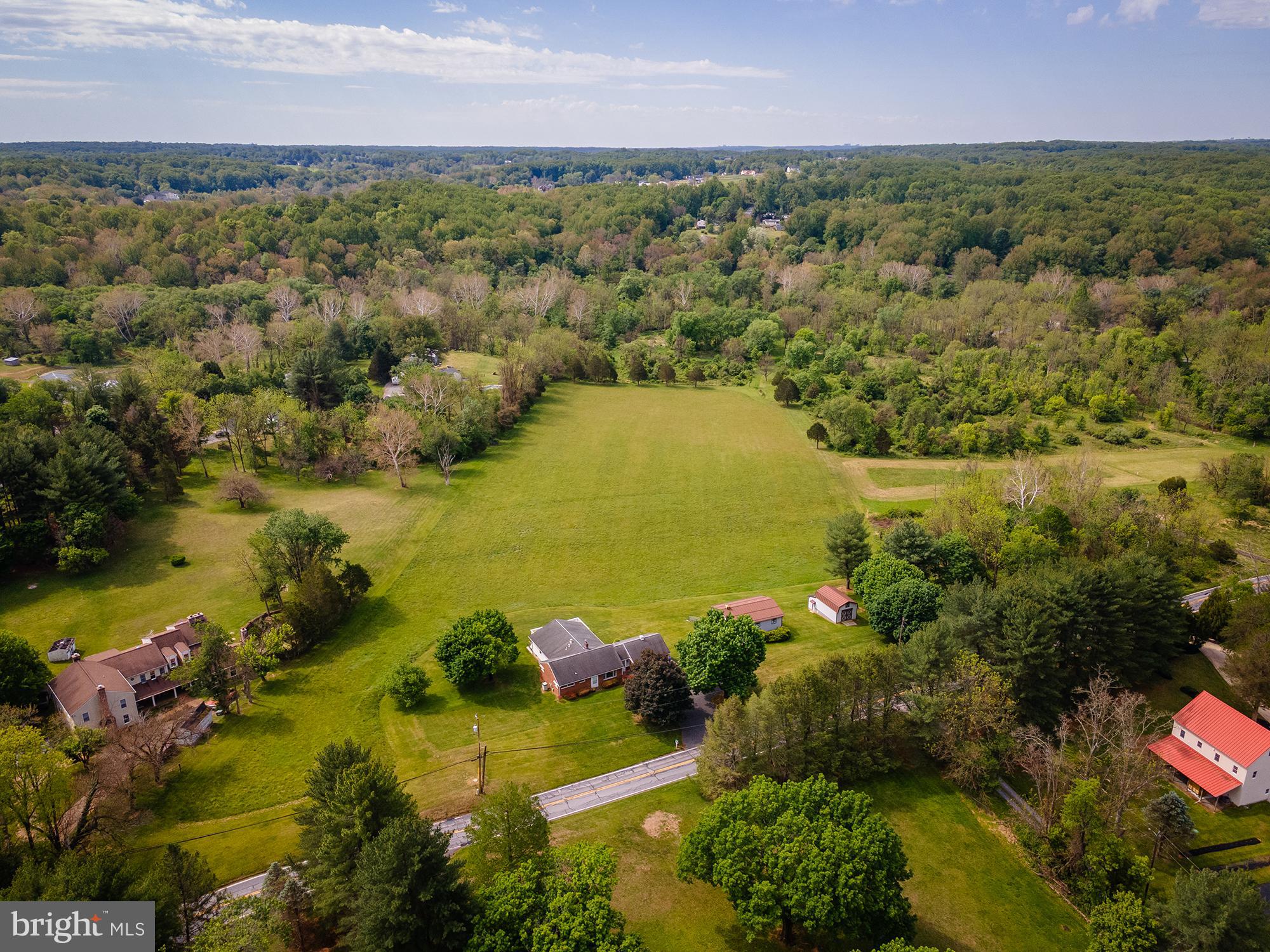 These opportunities do not come available often in Brookeville! Set on 9 flat grassy acres, 1112 Gold Mine Rd offers the space, outbuildings, versatility, and setting so many search for. The expansive brick ranch home features abundant natural light, a spacious kitchen/dining addition with stainless steel appliances, hardwood flooring, ample cabinetry, and a large rear deck overlooking the stunning property. The main level includes a large primary suite with expansive full bath, 2 additional bedrooms and full bathroom with shower/tub combo. There is a front facing living room and additional room perfect for an office, playroom, or additional living space. The mostly finished lower level adds additional living area with another spacious bedroom, full bath, laundry, lots of storage, and room for more living space to be finished out. Outside, the property continues to impress with an attached 2-car garage connected by a breezeway and multiple outbuildings offering exceptional storage, workshop, equipment, or hobby space — including a large detached building with finished upper-level space and covered parking below. It would be easy to add stalls into the bank building or follow whatever path your outdoor enthusiast heart desires. The acreage is simply beautiful and peaceful, gently sloped but surrounded by trees and quiet land creating the utmost sense of pastoral privacy and serenity, but a quick commute to DC, Baltimore, and the surrounding areas. The property backs up to government owned Parkland with access to trails - perfect for horseback riding or hiking.  Whether you’re dreaming of a homestead, hobby farm, or simply room to spread out and enjoy the outdoors, this property is packed with potential. No subdivision available.