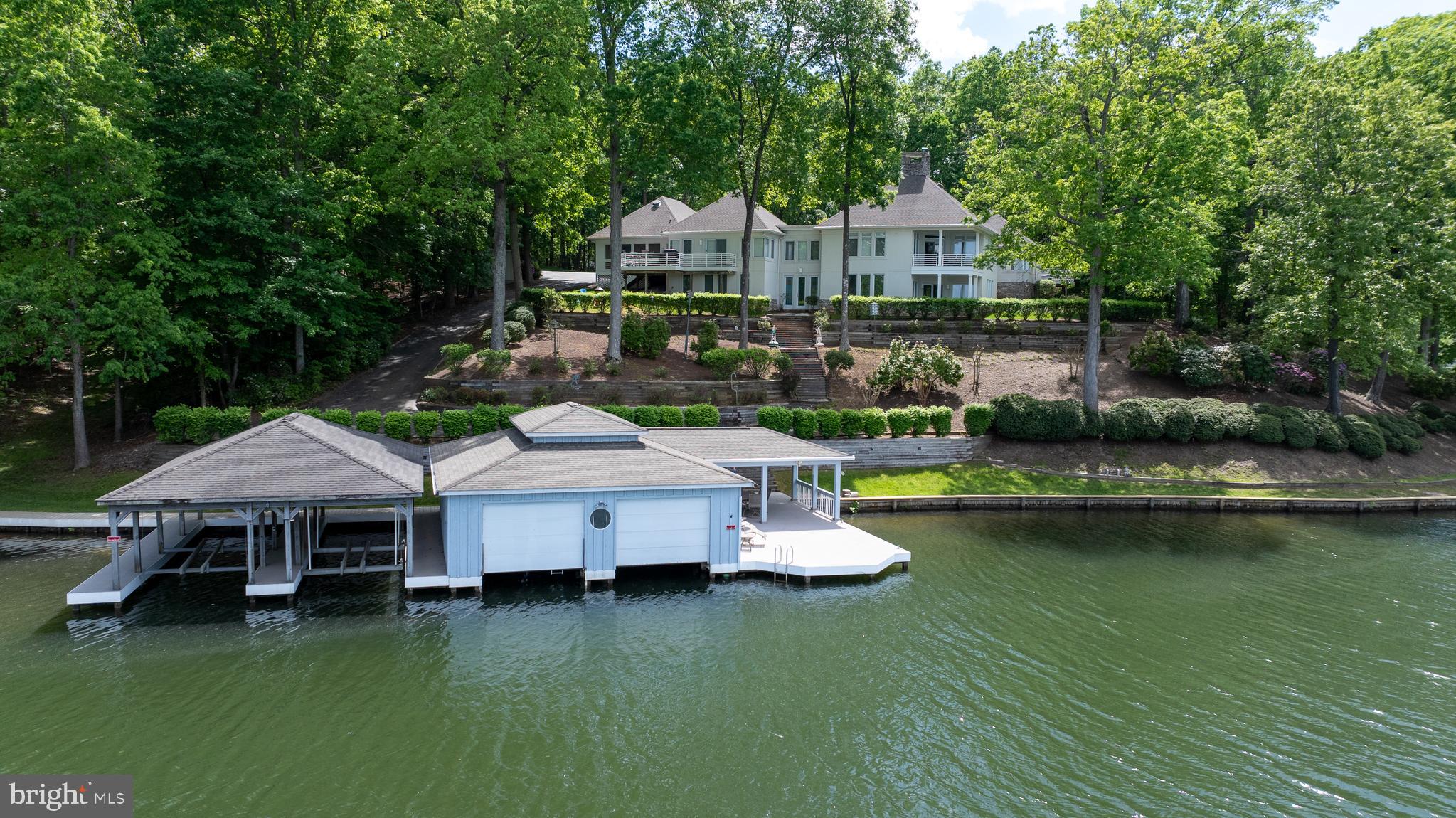 Discover this standout waterfront estate at Lake Anna, Virginia, that comes furnished and offers stunning panoramic lake views from nearly every room. Privately situated on 5.7 acres across three waterfront lots (LOTS 3, 4 & 5), this property presents a rare opportunity and endless possibilities.  Build a second house or guest house to have your own family compound with NO HOA! This custom-built retreat has over 500 feet of bulkhead shoreline and an impressive four-slip boathouse with composite decking (deep water 10+ feet). Two slips are enclosed to protect your watercraft, and all four are equipped with electric lifts. The boathouse also features a spacious sun deck, partially covered for shade, perfect for relaxing by the water. 5 bedrooms, 4 full baths. The main level showcases a family room with a double-sided stone fireplace, a large kitchen with granite counters, a center island with seating, a breakfast nook, and a separate dining room. Enjoy multiple living areas including a living room, two sitting rooms, and a spacious primary suite with a corner gas fireplace, walk-in closet, bath with jetted tub, separate shower and a private balcony overlooking the lake. The fully finished walkout basement expands your entertaining space with a family room featuring another double-sided fireplace, recreation area, wet bar, four additional bedrooms, and two full baths. Outdoor living is exceptional with a back deck, screened porch, covered porch with ceiling fan, and a lakeside fire pit to gather around with friends and family. Additional highlights include a gated entrance, long paved circular driveway, two-car attached garage, stone and stucco exterior, whole-house generator, lake-fed irrigation, storage shed, and a paved golf cart path down to the boathouse. Great location conveniently located less than five minutes from groceries and dining, and positioned mid-lake just south of the 208 Bridge. Come discover where unforgettable memories are made and lakefront living begins. Projected rental income in MLS documents!