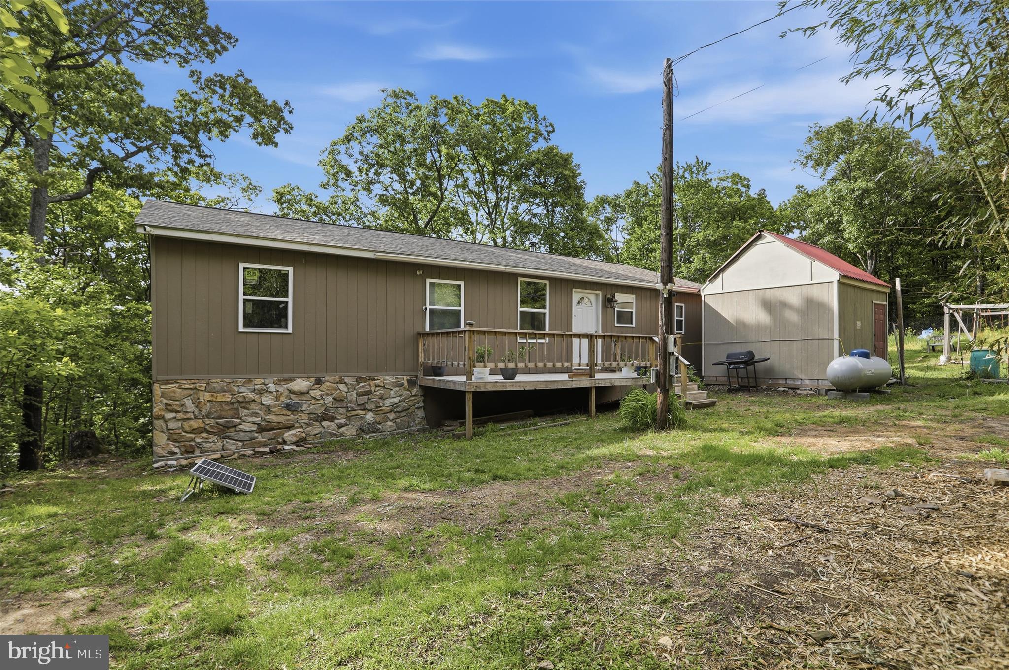 Your Mountain Retreat is Here! 1560 sq ft Ranch style home built in 2021, currently with solar energy and generator back up, providing that off the grid effect but with Lined Electric on site, should you decide to use it. No HOA here, this land is Unrestricted!  5 Acres of woodland with about 1/4 acre of fenced vegetable garden area, The location provides an excellent seasonal easterly view with the potential for an outstanding year long easterly vista with a little clearing. In the home, the Great Room  with its cathedral ceiling takes advantage of the view from its many windows and you'll love watching the critters stroll by. The Kitchen is spacious and centrally located. The solid wood trim throughout gives that warm country feel. All New flooring . This Home is large with the 3 Bedrooms and 2 Bonus rooms for den or office, bedrooms - you decide. Warm and comfortable with the wood heat / propane heater back up. If you looking to get away from the city and be a bit self sufficient this may just be the place for you. Make you appointment early as we need 48 hour notice, with NO Saturday showings, and please no shoes to be worn in the home.