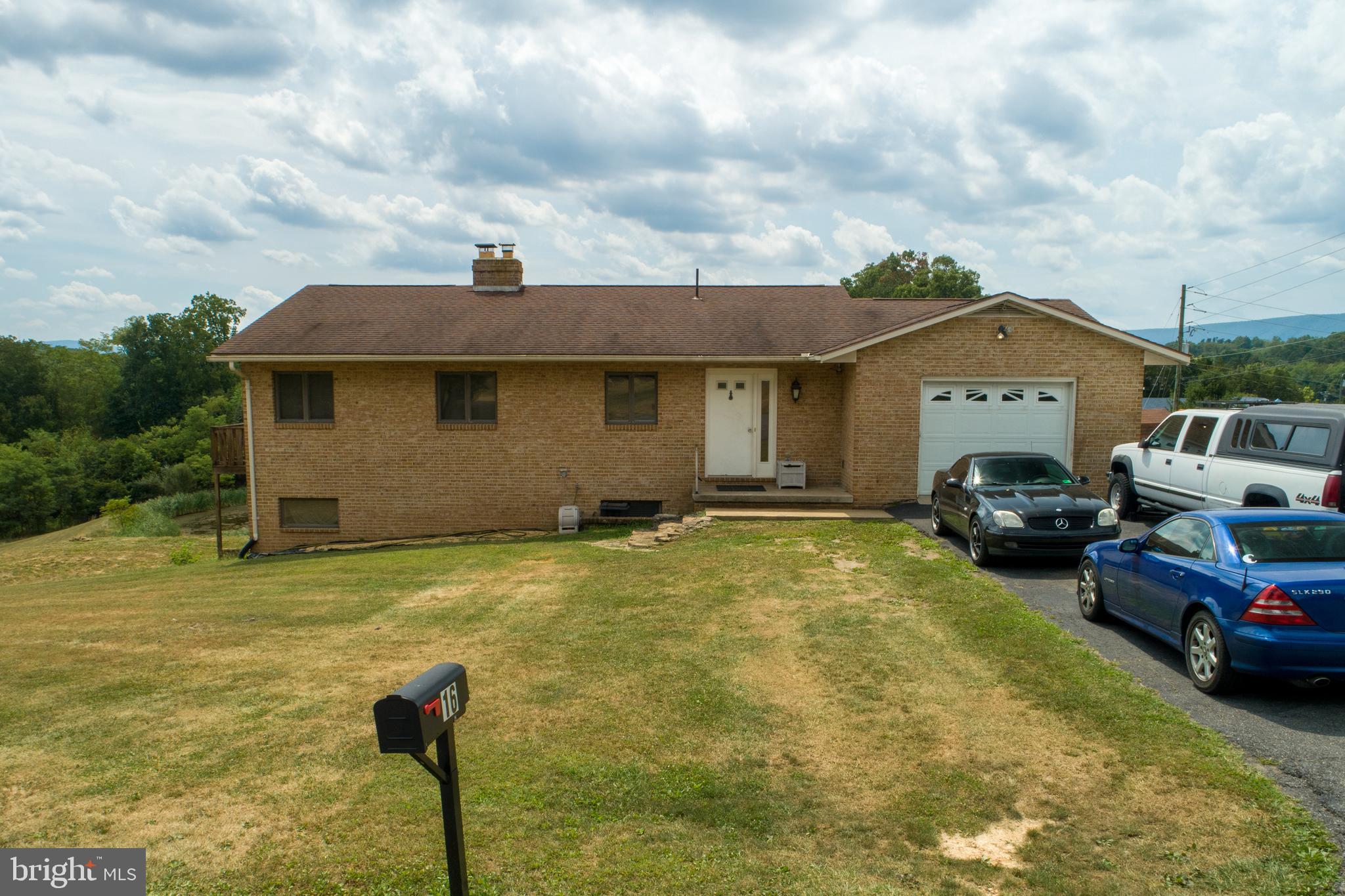 Lovely 3 bedroom 2 full bath brick home on 3.3 acres right outside the town of Berkeley Springs.    Excellent location and beautiful mountain views right off the paved road.  Mostly cleared property features stocked pond and gently rolling hills.  Basement has three walkouts, two of which are sliding glass doors onto two separate patios great for entertaining. House has two attached garages - one in the front of house and one at the rear of the house.  All kitchen appliances convey, washer and dryer and extra freezer in garage does not. Electric baseboard heat however, wood burning fireplace upstairs with blower and wood burning stove downstairs sufficiently heat home in winter.  Brand new HVAC as of this summer. New water heater as of last year.  Upstairs newly painted and new front door. Paved driveway fits 4 cars easily.  HOA maintains roads and plows snow. Recently renovated kitchen with all new stainless steel appliances. Hardwood floors on main level.  15 minutes from C&O canal biking trails.   40 minutes from Winchester VA, Martinsburg, WV and Hagerstown, MD.