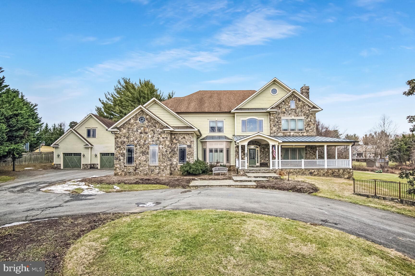 This lovely estate home blends timeless elegance with modern luxury on a picturesque 1.3-acre lot. The striking stone façade and wraparound porch create a serene retreat with every contemporary convenience. Inside, a soaring two-story foyer welcomes you with natural light on refinished hardwood floors. The chef’s kitchen boasts a spacious island, rich cherry cabinetry, and ample dining space. The main level features formal living with gas fireplace, and dining room, a grand family room with a fireplace, and a private office with an adjacent full bath—perfect as a guest suite.
With nearly 9,000 finished square feet and 10-foot ceilings, this home offers five spacious bedrooms with new carpet and 4 bathrooms upstairs, and an additional bedroom and bath on the lower level. The walkout english basement is an entertainer’s dream, featuring a granite-topped bar, full kitchen, custom built-ins, gym, office, and abundant storage.
Outdoor highlights include flagstone walkways, a screened-in back porch, and two garages accommodating five vehicles, plus a circular driveway for extra parking. Additional features include two full sized laundry rooms. Ideally located near Shady Grove Metro, I-270, Shady Grove Hospital, and premier shopping and dining, this exceptional home offers the perfect blend of luxury, comfort, and convenience. A rare find! Wootton HS Cluster!