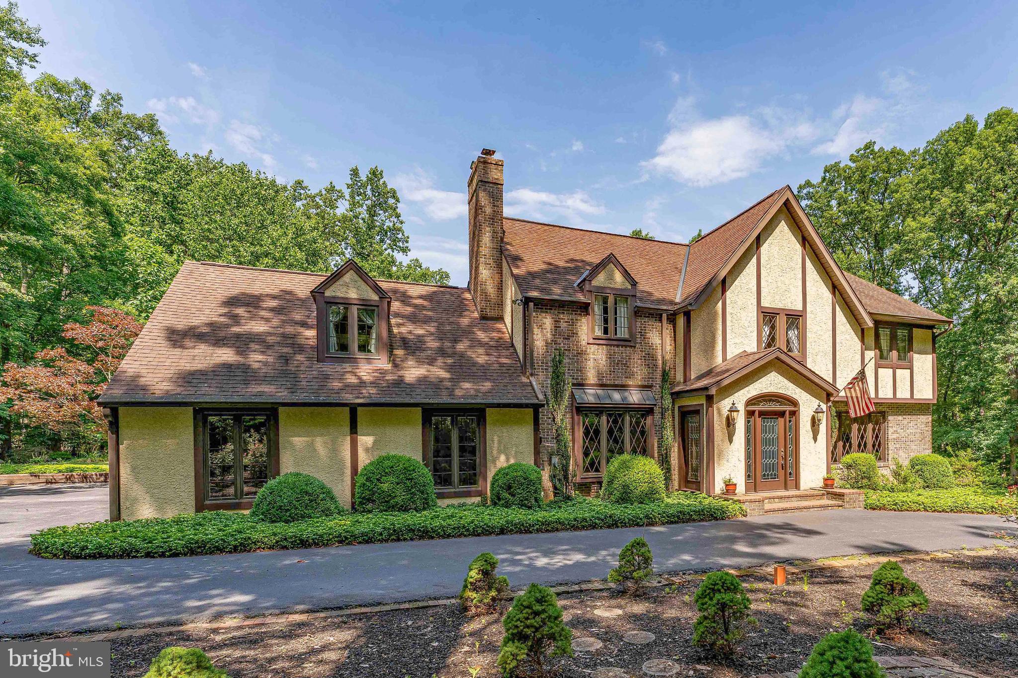 in the Fox Run neighborhood of Pottstown, set on 6 private acres backing up to French Creek State Park and near St. Peters Village. Offering 3,832 square feet of living space, a large circular driveway with parking for approximately 10 cars, an oversized 2-car garage, multiple fireplaces, generous room sizes, and exceptional privacy. This home is a rare opportunity for buyers looking for space, character, and a peaceful setting while still conveniently located near services. As you approach, mature trees, landscaping, and a quiet private setting create a welcoming first impression. Step inside through the brick vestibule and into the foyer with tile flooring and a ceiling light. To the right of the foyer, the living room offers hardwood floors, crown molding, recessed lighting, a fireplace, and a large front window that brings in natural light. Just beyond, the dining room features hardwood flooring, crown molding, a chandelier, and a charming side bay window. French doors lead from the dining room into the spacious all season sunroom, while a separate doorway provides access to the kitchen. The sunroom is one of the standout spaces of the home, featuring hardwood floors, vaulted ceilings with beams, skylights, a stone-surround fireplace, custom built-in cabinets and shelving, walls of windows, multiple chandeliers, and two sliding glass doors leading outside. With views toward the pool area and backyard, this room is ideal for relaxing, entertaining, or enjoying the secluded surroundings. The kitchen features hardwood flooring, quartzite countertops, solid wood custom cabinetry, stainless steel appliances, room for a breakfast table, and access to a butler’s pantry and a walnut slab full size wet bar with pendant lighting. The nearby family room adds another inviting gathering space with hardwood floors, a brick fireplace, ceiling beams, crown molding, wainscoting, and a triple front bay window with built-in bench seating. A convenient central powder room completes the main level. Upstairs, the spacious primary bedroom features wall-to-wall carpeting, a vaulted ceiling, dormer windows, ceiling fan, and access to a large walk-in closet area. The primary suite also includes a private sitting room with hardwood flooring, custom built-in cabinetry, and shelving, creating an ideal space for a reading room, office, dressing area, or quiet retreat. The en-suite bathroom features marble tile flooring, double sink vanities, and a step-in shower with views of the back yard. Three additional bedrooms provide comfortable accommodations for family, guests, or work-from-home needs, including one with built-ins and another with a built-in desk and shelving. A full hall bathroom with marble tile flooring, double sink vanity, skylight, and a clawfoot tub and separate shower completes the upper level. The lower level expands the living space with a large recreation room featuring vinyl plank flooring, computer desk, windows, and a ceiling fan with light. A dedicated laundry room includes built-in custom cabinetry, counter space, and front-load washer and dryer included with the home, while additional basement space provides room for storage, hobbies, utilities, or future possibilities. Outside, the property truly shines with 6 acres, mature trees, a large circular driveway, a brick patio off the sunroom, an in-ground pool, firepit, and a walking path leading to a shaded alpine pavilion with vaulted ceiling detail, beams, and a chandelier. With room to spread out and enjoy the outdoors, this property is ideal for entertaining, relaxing, hiking and gardening, or simply appreciating the tranquil privacy. Located in a quiet area bordering French Creek State Park and near charming St. Peters Village, this home offers the rare combination of acreage, privacy, character, and convenience. Don’t miss the opportunity to make 2323 Saint Peters Road your next home.