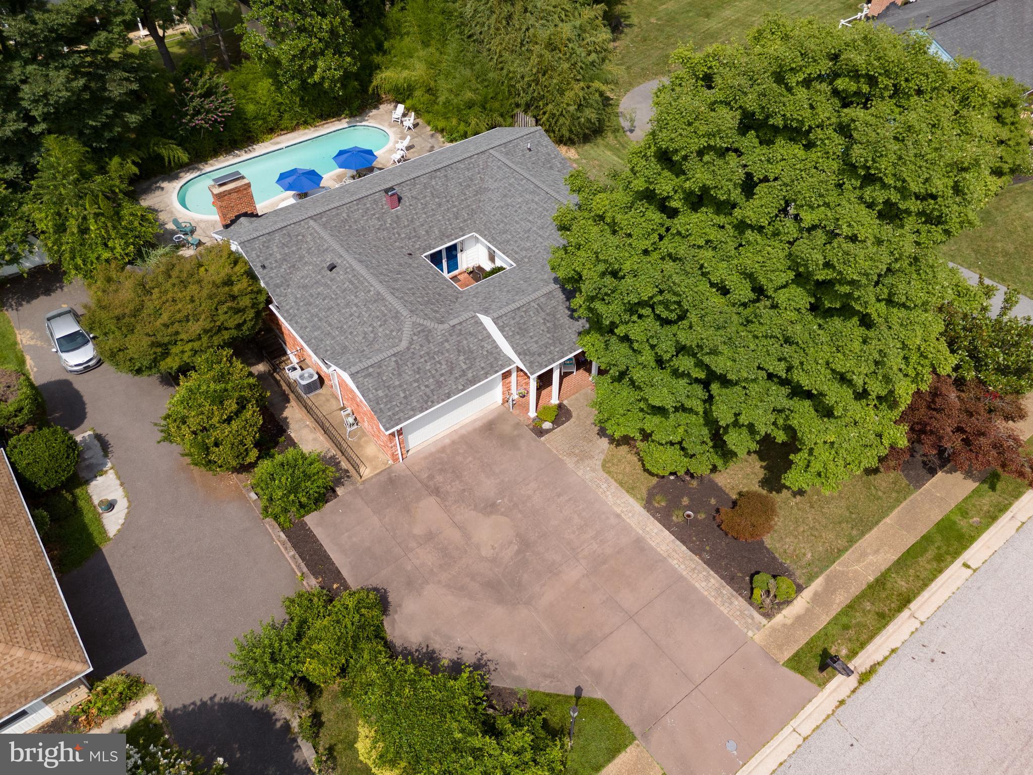 From the street, 2104 Cedar Circle Drive has a quiet, understated presence. Step through the wrought-iron gates, however, and the home immediately begins to reveal what makes it so special. A brick courtyard and striking blue double doors create a memorable entrance to this spacious brick rancher in Catonsville’s established Westerlee community.

Inside, the home has been beautifully maintained while retaining the character that gives it such personality. Slate flooring, graceful archways, original hardwoods, and parquet floors add warmth and architectural interest throughout. The expansive living and dining areas offer an open, flexible layout with abundant natural light and plenty of room for both everyday living and entertaining.

The generously sized kitchen is a true gathering space, featuring extensive cabinetry, double wall ovens, a gas cooktop set into the large center island, abundant counter space, and a breakfast area anchored by a stone wood-burning fireplace. French doors lead directly to the backyard, making the kitchen a natural connection between the indoor and outdoor living spaces.

Four comfortable bedrooms are located on the main level, including a spacious primary suite with beautiful parquet flooring and a private bath featuring extensive stonework and a large walk-in shower.

The finished lower level adds an exceptional amount of living space, with a huge family room and a separate bonus room that could function as a home office, guest room, possible 5th bedroom, or part of a private in-law or multigenerational suite. A full bathroom on this level makes the possibilities even greater.

Outside, the private backyard feels like its own retreat. Mature landscaping surrounds the in-ground pool and expansive patio, creating a peaceful setting for summer afternoons, outdoor dinners, and gatherings with family and friends.

Additional highlights include a two-car garage, a new furnace installed in 2025, and an architectural-shingle roof approximately seven years old. Filled with space, flexibility, and enduring character, this is a home that has been thoughtfully cared for and is ready for its next chapter.