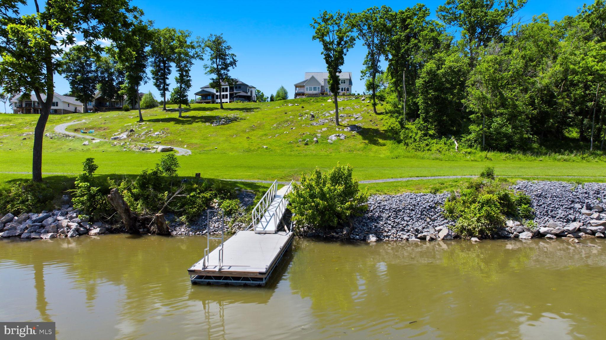 A rare offering on the deep-water Potomac, this custom waterfront residence pairs architectural presence, refined finishes, and a setting designed for life on the water. Located in the gated community of Potomac Overlook Estates, with access to 10 miles of deep-water boating, the property offers a level of privacy, scale, and waterfront experience seldom found in the area. From the covered stone front porch to the private decks, patios, and a private floating dock below, every element was designed to make the most of its riverfront setting. Inside, wide-plank LVP floors, soaring ceilings, and an open main level create an impressive sense of scale. The gourmet kitchen makes a strong impression with an oversized island, quartz countertops, farmhouse sink, and butler’s pantry, all opening to a breathtaking dining area wrapped in windows and oriented to the river. The living room is anchored by a dramatic floor-to-ceiling stacked stone fireplace with custom built-ins. All five bedrooms are true suites, each with its own ensuite bath, including a primary suite designed as a private retreat with a spa bath, soaking tub, dual vanities, and custom walk-in closet. A separate guest suite and loft add flexibility for extended stays without sacrificing comfort or privacy. Outdoor spaces are equally compelling, with a glass-railing deck, expansive tile patio, built-in fire pit, and terraced landscaping leading to the water’s edge and private floating dock. The oversized crawl space and basement area include a full bath, offering exceptional utility after long days on the river. Whether centered around boating, sunset dinners, or weekends filled with guests, this is a waterfront home designed to make the most of deep-water Potomac living.