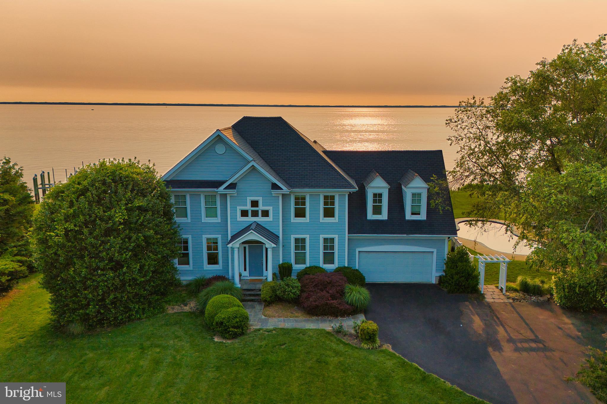 Welcome to a Chesapeake Bay retreat where spectacular views and unparalleled waterfront living await. Perfectly positioned on a serene cul-de-sac, this elegantly appointed home offers breathtaking vistas of the iconic Bay Bridge, majestic lighthouses, and sunsets that will leave you speechless.

Upon entering the two-story foyer, the formal living room and bonus room welcome you and provide ample space for unwinding or hosting guests. The thoughtfully designed interior offers four bedrooms and four and a half baths, including an upper-level primary suite with a cozy sitting room and a yacht-inspired bathroom. On the lower level, a fifth bedroom studio suite features an ensuite bath, sitting area, and granite bar top — ideal as an in-law or au pair suite. A separate entrance to the outdoors provides additional flexibility and privacy.

Natural light floods every room and frames the serene water views at every turn, accentuating the open-concept kitchen, dining area, and family room that flow seamlessly into the outdoor covered living spaces.

Three sets of oversized French doors open to the stunning waterside patios, featuring a PebbleTec saltwater heated pool, lush mature landscaping, and perfect elevation outside of the flood zone — a rare combination that enhances both beauty and peace of mind. A covered patio and pool cabana with a dedicated pool bath create the perfect environment for relaxing or entertaining as you take in the beauty of the bay.

The private dock with two boat lifts (12,500 lb and 30,000 lb) provides endless opportunities for fishing, crabbing, and boating, completing the ultimate waterfront lifestyle.

This home is more than a residence—it’s a masterpiece of design and nature, crafted to immerse you in the soothing rhythm of life on the bay.

Welcome Home.