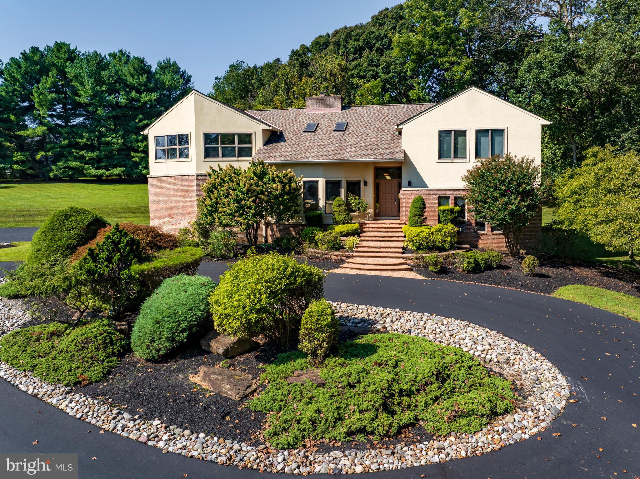 Welcome to your private retreat in one of the area’s most sought-after communities! This one-of-a-kind custom home offers a truly unique living experience that will make you feel like you are on vacation every day. Featuring five bedrooms and three full bathrooms spread across four thoughtfully designed levels, this home provides generous space, flexibility, and privacy for every lifestyle. Nestled on over 4 acres of beautifully landscaped grounds that back to woods, this setting offers tranquility and seclusion while still being conveniently located near everything you need. From the moment you step inside, you are greeted by soaring two-story vaulted ceilings with wood planks, skylights, and an abundance of natural light throughout. The main level features an impressive front living room with a stacked-stone fireplace that is double-sided and shared with the kitchen, creating a warm, welcoming ambiance. A wet bar area off the living room is perfect for entertaining guests. The expansive eat-in kitchen is a chef’s dream, fully equipped with stainless steel appliances, granite countertops, ample storage space, and a dining area with access to the deck that overlooks the backyard and woods. Completing this level is a laundry room with a pantry and access to the two-car garage. Upstairs, the primary bedroom suite is a true escape with a cathedral ceiling, a luxurious en-suite bathroom that includes a jetted tub and walk-in steam shower, along with a large walk-in closet and dressing vanity area. Three additional bedrooms and a second full bathroom complete the upper level. A few steps down from the foyer, the lower level includes a spacious family room and a fifth bedroom with a door to the third full bathroom. A versatile bonus room on this level is ideal for an office, playroom, or even another bedroom. Down a few more steps, the basement level provides even more flexibility with a recreation room and a large office with built-ins. A large utility room adds more storage space. Enjoy spending time outside on the spacious deck with an expansive backyard that has space for everyone’s outdoor activities. Don't miss this rare opportunity to own a spectacular property that combines architectural distinction with a serene, resort-like atmosphere. Additional highlights include zoned heating and cooling systems, two water heaters, and a generator.