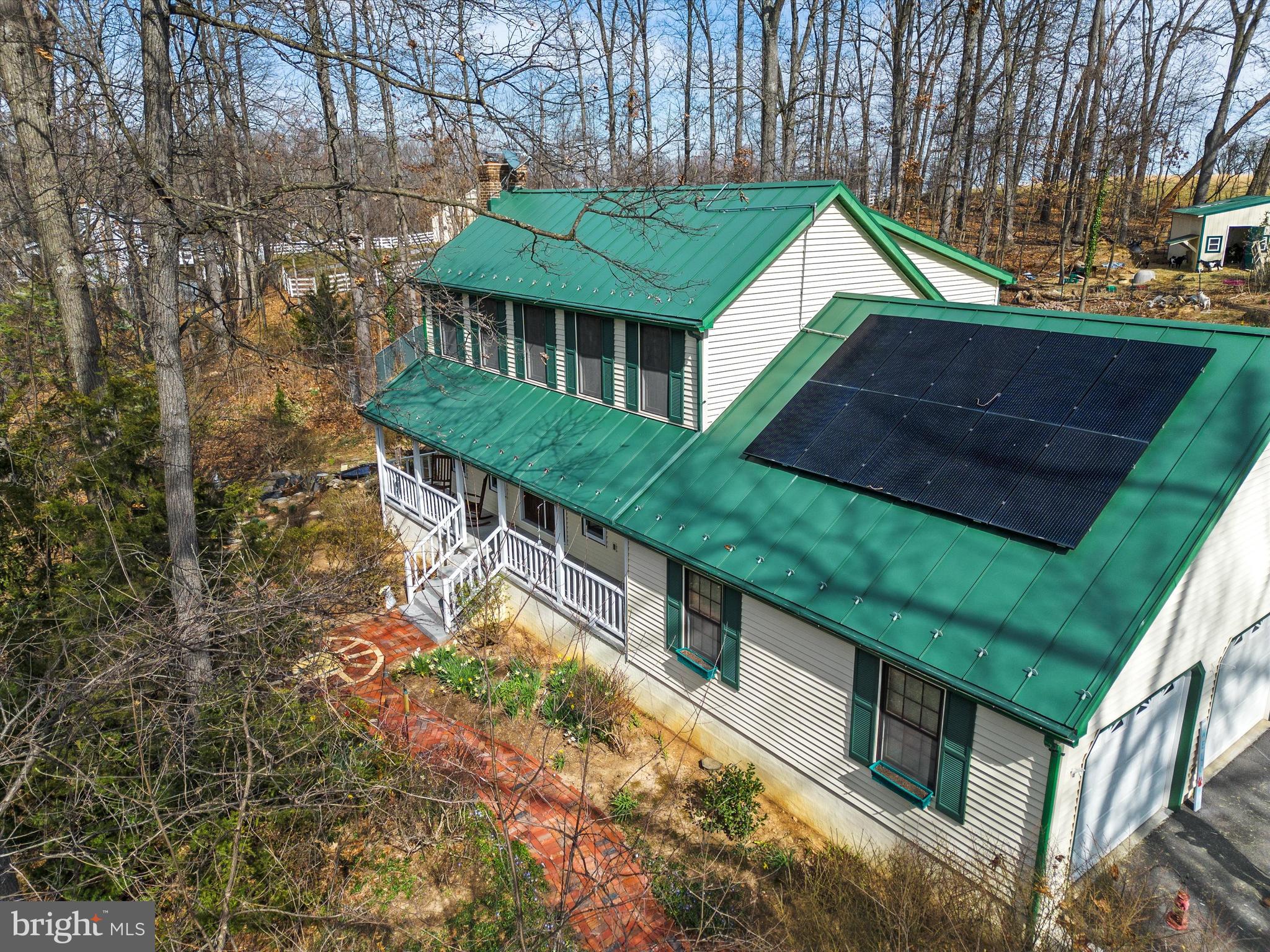 Enlarged 2790 (est) square foot colonial on 5 wooded acres in secluded subdivision south of Winchester, VA with newer metal roof &  roof mounted solar system that conveys.  Major first floor renovation project in 2018 includes....abt 464 feet of added  finished space  in Kitchen and dining  (8x34')area on rear.  The rooms were renovated and enlarged  by 8 feet across the back of house with an added heated 12x16  Florida/Sun room looking out on treed lot that features a EZ Breeze windows and French doors, new first floor windows & 2 new high efficiency heat pump systems. Main house system features efficient variable speed fan. The new kitchen features a custom 2 level island with bar sink and pull-out knife storage, custom back splash and granite counters, farm style sink, oil rubbed bronze fixtures and accents, walk in pantry with a custom installed antique stained-glass window, 2 electric ovens with a propane range. Maple hardwood floors installed throughout. The living room includes a wood stove and built in shelves on either side of stacked stone inset wall behind the woodstove. The 2.5 bay attached side load garage includes a workbench and shelves. It has basement entry, a door to the front porch and a pull-down stairs to the attic. Concrete stamped patio, front walkway made from bricks from the old Winchester Woolen Mill. Custom barns/outbuildings include a goat barn with sleeping shelf, hay racks and storage, Large coop on other end and secure outdoor chicken run, large area fenced with electric and wire fencing, a run in shed, brick steps leading to barn and sheds, 2 storage sheds & double decorative ponds. Radon remediation installed in basement. Main level den/office or 4th bedroom. The central vac unit is as is and does not operate.  Seller provided 3 bedrm septic permit. Copy in MLS documents. Seller states solar panels covers house electric use on  most sunny days with excess exporting to Rappahannock  Elec Coop. Battery back up can be added.