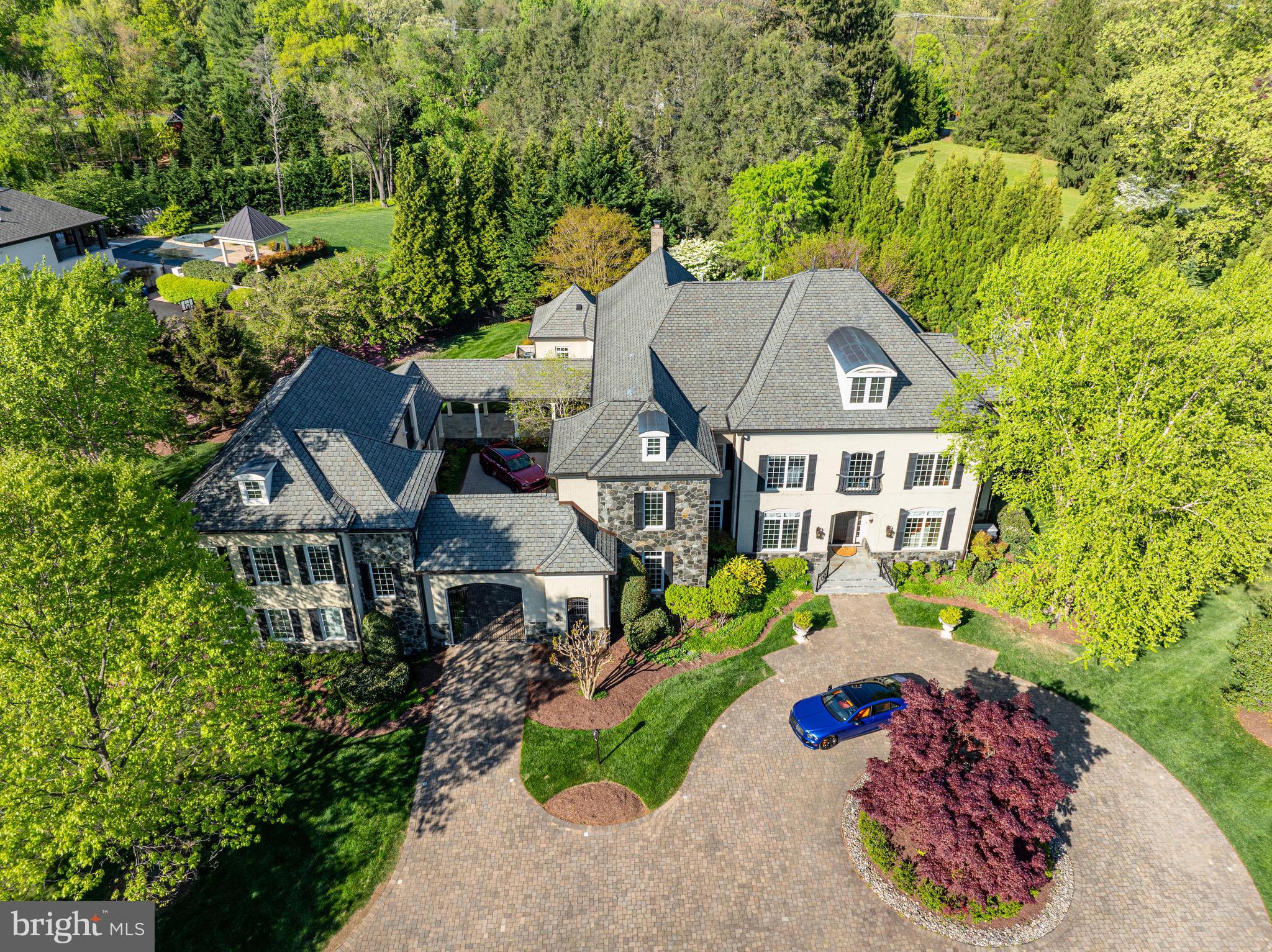 This enchanting French Colonial estate spans over 11,000 square feet and graces a 1.73-acre hilltop located only minutes to Tysons Corner and McLean. This Keswick Model Home is nestled among mature landscaping and lush gardens, the main residence comes with a 2-story carriage house perfect for those who need additional privacy and a separate living quarters. The main residence offers five generous bedrooms, including a spacious primary suite with a separate sitting room and private terrace overlooking the verdant surroundings. The home is a haven of luxury, featuring multiple living and entertainment areas, two kitchens equipped with an AGA range, Subzero refrigerators, and Miele appliances. With six fireplaces, a complete spa, a Sonos sound system with 14 zones, a home generator, and a movie theater, every detail is designed for indulgence. A covered breezeway links the main house to the carriage house, which includes a full kitchen, two bedrooms, a full bath, and a powder room. The fully gated, circular motor court ensures secure parking and grants access to the adjoining four-car garage. Additional parking is available along Towlson Road. In the private garden, an expansive stone terrace, framed by lush landscaping, features an outdoor fireplace. Nearby, a serene fountain and soothing waterfalls add to the tranquil ambiance. Situated within the Langley/Cooper school pyramid and just minutes to McLean and Tysons Corner, this estate is a rare gem in one of the region’s most coveted locations.