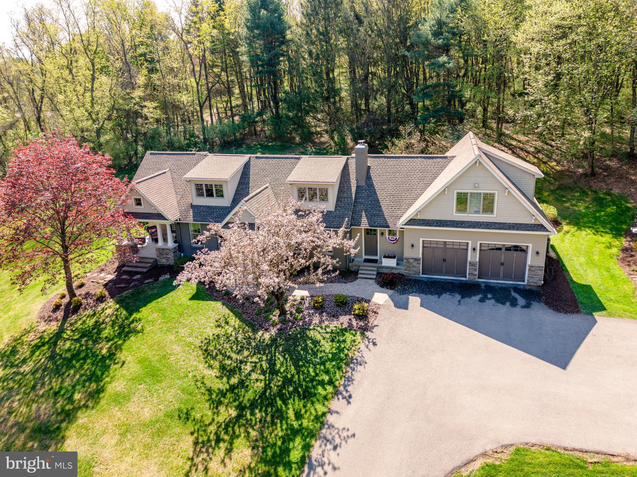 Nestled on nearly 3 breathtaking acres in highly desirable Upper Saucon Township, this extraordinary 3,600-square-foot Cape Cod with 4 bedrooms and 4 full baths has been completely renovated to offer the perfect blend of modern sophistication and timeless charm. Surrounded by mature trees, flowering dogwoods, vibrant perennials, and peaceful wooded views, this remarkable property feels like your own private nature sanctuary. Thoughtfully redesigned and meticulously maintained, the home is filled with natural light streaming through quality Pella and Andersen windows, creating bright and inviting spaces throughout. Zoned heating and cooling provide year-round comfort and efficiency. At the heart of the home is a stunning modern farmhouse kitchen featuring custom cabinetry, built-ins, granite countertops, a tumbled tile backsplash, and an impressive 9-foot center island designed for gathering, entertaining, and everyday living. The adjacent family room is equally impressive, highlighted by a gas fireplace and walls of windows that showcase the surrounding landscape and bring the outdoors in. Elegant formal living and dining rooms offer additional spaces for hosting family and friends. With four spacious bedrooms and four full baths, the home offers exceptional versatility. A rare and highly sought-after feature is the presence of two luxurious primary suites—one conveniently located on the first floor and another on the second floor—providing ideal accommodations for multi-generational living, extended family, guests, or long-term flexibility. The first-floor suite features a private entrance, full bath, and its own covered patio, creating a peaceful retreat with endless possibilities. The partially finished walk-out lower level adds valuable living space and includes a charming wood-burning fireplace, making it perfect for a recreation room, home office, fitness area, media room, or play space. Car collectors, hobbyists, and outdoor enthusiasts will appreciate the impressive garage accommodations. In addition to the attached two-car garage, the property features a detached two-story, three-bay barn type/garage with electric service, propane heat, water, electric and cable. Ample space for vehicles, equipment, an RV, or boat. The upper level presents exciting opportunities for a workshop, studio, home business, or creative retreat. Rarely does a property offer this unique combination of modern updates, flexible living arrangements, exceptional outbuildings, and such a spectacular natural setting. Experience refined country living with the convenience of nearby shopping, dining, major commuter routes, and all the amenities the Lehigh Valley has to offer.
