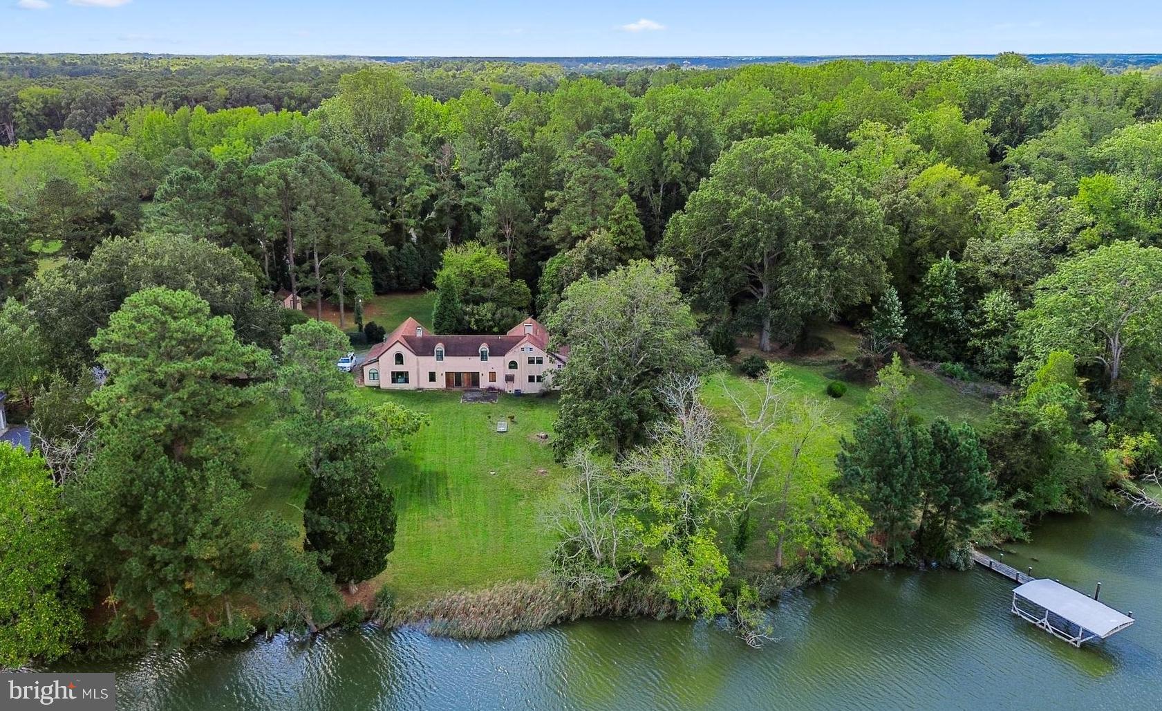 Designed by William Draper Brinckloe, one of Easton’s best early 20th Century architects, this Mission house, “Edgemar”, is nestled on a private 4.5-acre double lot and offers an exceptional blend of character, comfort, and serenity. The property boasts a dock with a highly coveted boathouse (that can no longer be built), a natural shoreline, and mature landscaping highlighted by 100-year-old boxwoods, flowering magnolias, lush hydrangeas, and a majestic 100-year-old oak tree. Renovated in 2008 with premium finishes, the home features top-tier appliances and fixtures from Miele, KitchenAid, Fisher & Paykel, and Kohler, complemented by Pella windows and sliding doors. Additional highlights include a roof with 50-year architectural shingles, underground electrical wiring, and beautifully preserved original brick floors. This 4,000+ square foot Spanish-inspired home masterfully balances preserved historic features with modern amenities. The gourmet kitchen is a true showpiece, featuring a Miele steam oven, cooktop with barbecue grill, two Fischer Paykal dishwasher drawers, imported Italian ceramic tile, and a custom, cement island topped with an inlaid Chesapeake Bay fossil—perfect for entertaining or  everyday use. The home offers generous gathering spaces including a grand living room, great room, dining area, and cozy library. Period details have been thoughtfully retained, including original heart pine floors, Delft tiles, antique tiles salvaged from Easton’s historic roadways, and a charming antique bar complete with copper sink. The home boasts two primary suites, one upstairs, and a secret bedroom hidden off the kitchen on the main level, and two convenient laundry facilities. Upstairs, you’ll find three bedrooms, three full bathrooms including a luxurious spa-like bathroom, two sleeping porches, and a versatile flex space ideal for a home theater, playroom, or den. The septic system is approved to accommodate 5 bedrooms. Completing the property are a detached two-bay garage with John Deere lawnmower, circular driveway, and a powered storage shed—offering functionality as well as timeless Eastern Shore charm. This historic home is rich with character and ready for your personal vision to bring it to life. Easton, Maryland, known as the New Hamptons of the Chesapeake Bay by Forbes Magazine, is conveniently located 1.5 hours from D.C. and Baltimore, and 2 hours from Philadelphia. Just minutes from fine dining, shopping, healthcare, theatres, galleries, museums, golf courses, a country club, a yacht club, and a jet airport.