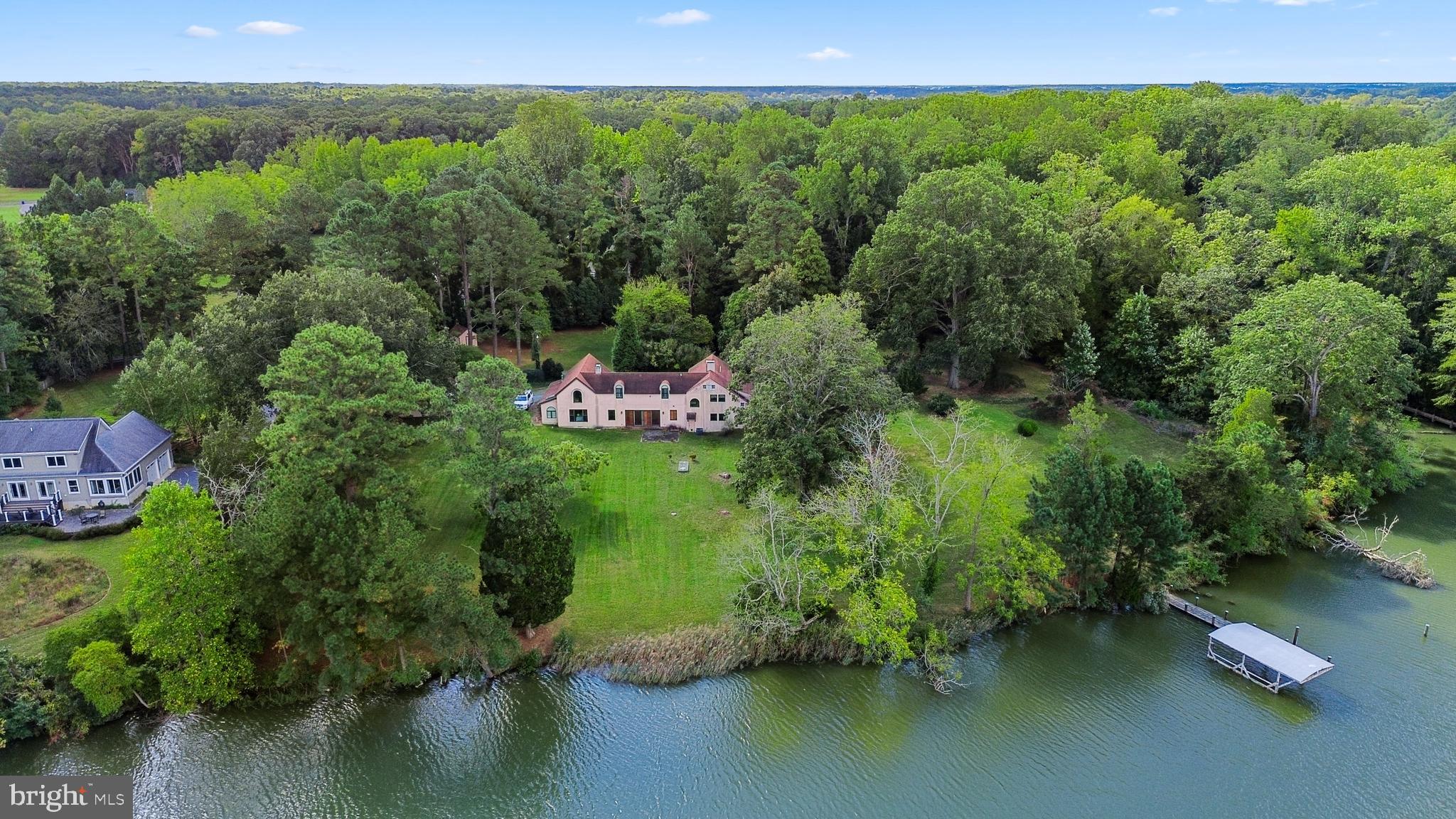 Designed by William Draper Brinckloe, one of Easton’s best early 20th Century architects, this Mission house, “Edgemar”, is nestled on a private 4.5-acre double lot and offers an exceptional blend of character, comfort, and serenity. The property boasts a dock with a highly coveted boathouse (that can no longer be built), a natural shoreline, and mature landscaping highlighted by 100-year-old boxwoods, flowering magnolias, lush hydrangeas, and a majestic 100-year-old oak tree. Renovated in 2008 with premium finishes, the home features top-tier appliances and fixtures from Miele, KitchenAid, Fisher & Paykel, and Kohler, complemented by Pella windows and sliding doors. Additional highlights include a roof with 50-year architectural shingles, underground electrical wiring, and beautifully preserved original brick floors. This 4,000+ square foot Spanish-inspired home masterfully balances preserved historic features with modern amenities. The gourmet kitchen is a true showpiece, featuring a Miele steam oven, cooktop with barbecue grill, two Fischer Paykal dishwasher drawers, imported Italian ceramic tile, and a custom, cement island topped with an inlaid Chesapeake Bay fossil—perfect for entertaining or  everyday use. The home offers generous gathering spaces including a grand living room, great room, dining area, and cozy library. Period details have been thoughtfully retained, including original heart pine floors, Delft tiles, antique tiles salvaged from Easton’s historic roadways, and a charming antique bar complete with copper sink. The home boasts two primary suites, one upstairs, and a secret bedroom hidden off the kitchen on the main level, and two convenient laundry facilities. Upstairs, you’ll find three bedrooms, three full bathrooms including a luxurious spa-like bathroom, two sleeping porches, and a versatile flex space ideal for a home theater, playroom, or den. The septic system is approved to accommodate 5 bedrooms. Completing the property are a detached two-bay garage with John Deere lawnmower, circular driveway, and a powered storage shed—offering functionality as well as timeless Eastern Shore charm. This historic home is rich with character and ready for your personal vision to bring it to life. Easton, Maryland, known as the New Hamptons of the Chesapeake Bay by Forbes Magazine, is conveniently located 1.5 hours from D.C. and Baltimore, and 2 hours from Philadelphia. Just minutes from fine dining, shopping, healthcare, theatres, galleries, museums, golf courses, a country club, a yacht club, and a jet airport.