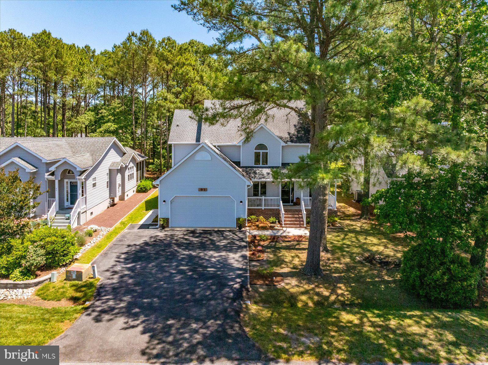 This beauty of a home has been extensively renovated in 2025 with numerous tasteful upgrades. A generous wrap-around front porch beckons you to enjoy views of peaceful Manklin Creek across the street! Extra tall Andersen windows invite the outside into the living room,  featuring white oak flooring, a beautiful ceramic tile fireplace surround, and an Anderson French door, which offers easy access to the huge rear deck and spacious yard. The stunning kitchen includes leathered granite countertops, a coffee bar with wine cooler, new appliances and a new 32 inch Ruvati  stainless steel workstation sink , new lighting, and 24 x 24“ ceramic tile flooring.  You will find a custom wood countertop surface, mounted cabinetry and wood pantry shelving in the laundry room with front loading washer and dryer.  An additional bonus room on the main floor, currently functioning as a sitting room and library, features a water view for morning  coffee or curling up late afternoon with a book. Restored wood pocket doors offer the opportunity for it to function as an office as well. The spacious and light filled primary bedroom offers two ample sized walk-in closets featuring installed custom closet systems. A completely renovated primary bath contains  cabinetry with vast storage, granite countertops with dual porcelain under mounted sinks, extra large mirrors, and a custom fully tiled shower with built-in bench plus custom glass enclosure. Three additional bedrooms all feature tall Andersen windows and roomy closets. The third bedroom includes a large 8 x 6 walk-in storage closet and vaulted ceiling.  One additional full bathroom contains a tub shower, new wood vanity, and ceramic sink, new lighting, mirror, toilet, and new ceramic tile flooring. The powder room contains all of the same renovations. There is parking for two cars in the finished garage including a built-in utility sink,  ample counter space, cabinetry, and an insulated garage door. Extras include new interior paint, professionally encapsulated crawlspace with dehumidifier, whole house carbon filter water filtration system, gas furnace, electric HVAC with gas back up, tankless gas water heater, new oversized metal switches  and outlet covers.  You will love entertaining in your flat,  spacious backyard, including an inlaid fire pit patio, extra large deck, and garden shed. All located on a quiet street with friendly neighbors, in the amenity-filled Ocean Pines community!