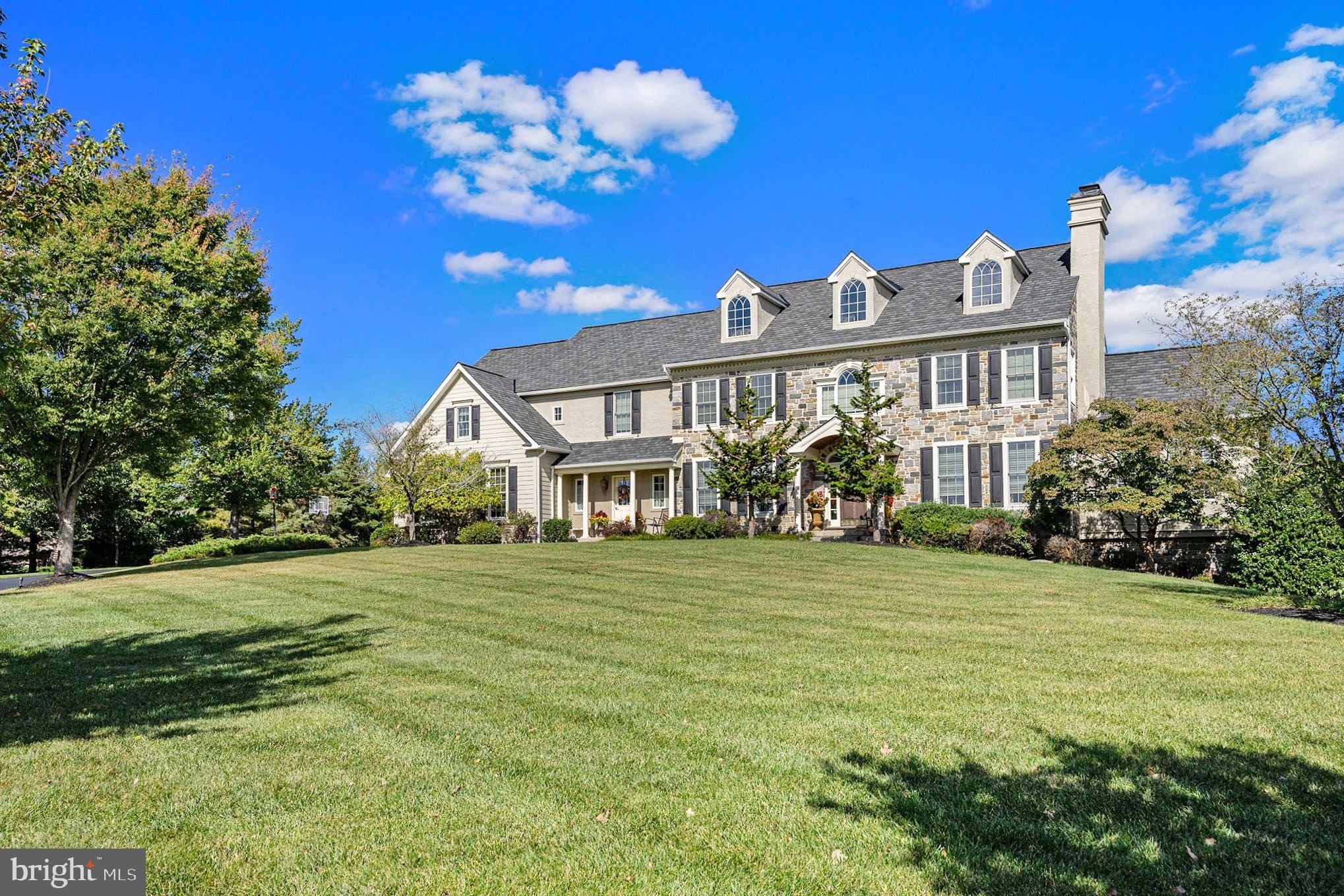 Gracefully positioned on nearly two acres of meticulously landscaped grounds within the prestigious Ashbourne Estates community, this exceptional Nottingham Country Manor estate, the community's previous model home, blends timeless architecture, refined craftsmanship, and resort-inspired living. Offering 5 bedrooms, 5 full baths, 2 half baths, and extraordinary indoor and outdoor entertaining spaces, this distinguished residence delivers an unparalleled lifestyle experience within the highly regarded Souderton Area School District.

Beyond its stately façade and manicured grounds, a world of elegance unfolds. Rich hardwood flooring, soaring ceilings, dramatic archways, custom millwork, and abundant natural light create an atmosphere of sophistication throughout the home's thoughtfully designed living spaces.

At the heart of the residence, the gourmet kitchen is both beautiful and functional, featuring granite countertops, custom cabinetry, stainless steel appliances, double wall ovens, a GE Monogram gas cooktop, decorative vent hood, expansive center island with prep sink, and a generous walk-in pantry concealed behind French doors. The adjoining breakfast room overlooks the spectacular rear grounds and provides seamless access to outdoor living spaces.

The impressive great room is anchored by a magnificent floor-to-ceiling stone fireplace, soaring volume ceilings, custom built-ins, and walls of windows that frame picturesque views of the estate's private outdoor sanctuary. Nearby, a richly appointed executive library showcases custom wood paneling and floor-to-ceiling oak bookcases, while the sunlit conservatory offers a peaceful retreat surrounded by panoramic garden views.

The luxurious primary suite sanctuary serves as a private escape, featuring a spacious sitting area, tray ceiling, crown molding, dual walk-in dressing rooms, and a spa-inspired bath complete with dual vanities, soaking tub, oversized shower, and elegant finishes. Additional accommodations include generously sized secondary bedrooms, a private princess suite, Jack-and-Jill bedrooms, and a secluded guest or bonus suite with its own full bath and walk-in closet.

The expansive daylight lower level offers exceptional flexibility for entertaining and everyday enjoyment. Complete with a recreation lounge, fireplace, full bath, private office, and an impressive wet bar featuring granite countertops, custom cabinetry, stainless appliances, and a center island, this level is perfectly suited for gatherings of any size.

Designed to rival a private luxury resort, the outdoor living experience is truly extraordinary. The resort-inspired grounds showcase a spectacular inground saltwater pool and spa surrounded by expansive stone terraces, lush landscaping, mature privacy plantings, cascading water features, and multiple areas for lounging and entertaining. A paver patio provides the perfect setting for outdoor dining, while the custom stone fireside lounge creates a warm and inviting destination for evenings under the stars.

Completing this remarkable offering is a three-car attached garage, extensive driveway parking, professionally landscaped grounds, and a coveted location within Ashbourne Estates. Combining timeless elegance, exceptional craftsmanship, and resort-style amenities, this extraordinary residence presents a rare opportunity to experience luxury living at its finest.