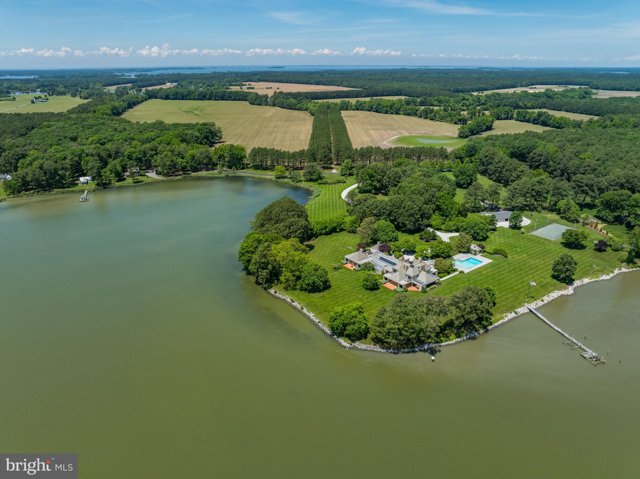 Welcome to Sunnyside, an exceptional and rare waterfront estate situated on a spectacular 16-acre point along the majestic Miles River.

A picturesque, winding driveway leads to the one-of-a-kind contemporary home, built by A. James Clark for his family. Completed in 1978, Sunnyside was the culmination of a 3-year collaboration between the legendary builder and philanthropist, his son, architect Paul Clark, and prominent DC architect, John Henry Sullivan. Mr. Clark hand-picked every remarkable detail on the property, from the materials to the craftsmen, many of whom would later join him to form the iconic Clark Construction.

Meticulously maintained over the years, the main house features floor-to-ceiling windows throughout offering stunning water views from every room. The thoughtfully designed layout of the main level easily accommodates both large and intimate gatherings. Highlights include a striking 24ft x 24ft sun-drenched atrium, an expansive main level primary bedroom suite complete with its own fitness room and sauna, 4 fireplaces, a living room with 20ft+ tall ceilings, a greenhouse, and a temperature-controlled wine room. The Great Room, the perfect spot for a casual gathering with friends and family, boasts striking custom woodwork throughout and incredible expansive western views of the property.

The second-floor features three bright and sunny bedrooms, each with their own private bathroom, balcony, fireplace, heating systems, and distinctive views of the Miles River.

The portico along the front of the home leads to an easily accessible, but completely private guest house with its own cozy living room, bedroom, full bath, fireplace, and kitchenette. Just outside the main house with idyllic garden and river views is the pool with its own full bath. The tennis court, livestock barn, and equipment barn are just a short stroll through the carefully designed and bucolic landscape.

Resting on a point on the Miles River, Sunnyside boasts approximately 2000ft of waterfrontage, of which approximately 1550ft is riprapped. A 135ft deep-water pier (approx. 6 ft MLW) offers 2 boat lifts. Less than 10 minutes to Downtown Easton and just a short boat ride (or less than 15 minutes by car) to St. Michaels, legendary Sunnyside proudly sits at the heart of Maryland’s Eastern Shore.