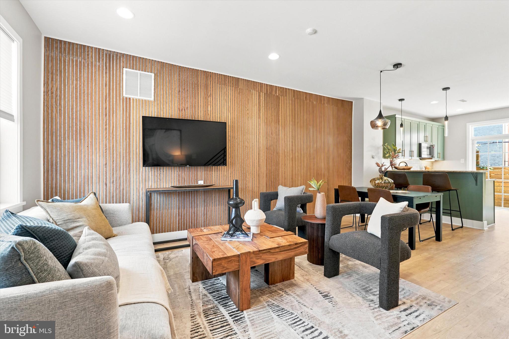 Set at the top of Point Breeze — one block from Graduate Hospital, 1722 Alter Street is a study in urban style done right. This 3-bed, 2.5-bath approx 2000'ft townhome nails the balance of urban style, warmth, and polish, and it's wider than most homes in its price range, giving you room to actually live, not just decorate.
The main level sets the tone immediately: a floor-to-ceiling acoustic wood slat accent wall anchors the living area, adding warmth and texture without losing its edge. The open layout flows straight into a fully renovated kitchen, where sage-green custom painted cabinetry, a two-tier granite peninsula, GE Cafe Series Range/Microwave and bonus pantry closet create a space built for both cooking and hosting. Refinished solid red oak floors (finished to read like white oak) run throughout, tying the whole level together with a clean, current look. Head downstairs and the personality kicks up a notch — a gorgeous custom black walnut bar with leather stools, built in mirror, and mini fridge turns the lower level into a legitimate hangout spot, not an afterthought. There’s a full egress window and plenty of room for a sectional, big screen TV, or a bedroom set if a 4th bedroom is required. One level up from the main you’ll discover 2 ample sized bedrooms with large closets and an updated full bathroom. The 3rd floor primary suite delivers a peaceful retreat with a built-in window bench, a walk-in closet outfitted with a custom California Closet system, and an updated bath with oversized shower. Every room has been freshly painted in custom colors, giving the whole home a considered, cohesive feel. Outside, you get two separate ways to enjoy the city. A private fenced patio — framed by new horizontal wood fencing- is ready for morning coffee or evening drinks. Up top, the roof deck delivers true 360-degree views, including an unobstructed shot straight to the Center City skyline, and complete with new fiberglass roofing. Location is everything here — and this one delivers. You're minutes from neighborhood favorites like American Sardine Bar, Chicks and On Point Bistro, an easy walk to Ultimo Coffee for your morning fix, and close enough to walk to iconic Rittenhouse Square and Center City on a nice day. Wharton Square and the Keith Haring mural garden are both nearby for green space and a little local flavor, as well as Carpenter Green Park with a misting pergola, a dog-friendly area, and a Little Free Library. Enjoy all that Graduate Hospital has to offer but without the Grad Hospital pricetag! All of this and just blocks from Sprouts, Target, Starbucks, public transit and a super easy drive to University City, Navy Yard, the Stadiums and the airport makes this an unbeatable location for professionals, families, and investors alike.  The walkability of a true urban neighborhood - blending the best of luxury, lifestyle and location. This is a home for someone who wants sharp design, real craftsmanship, and a location that puts the city at their feet.