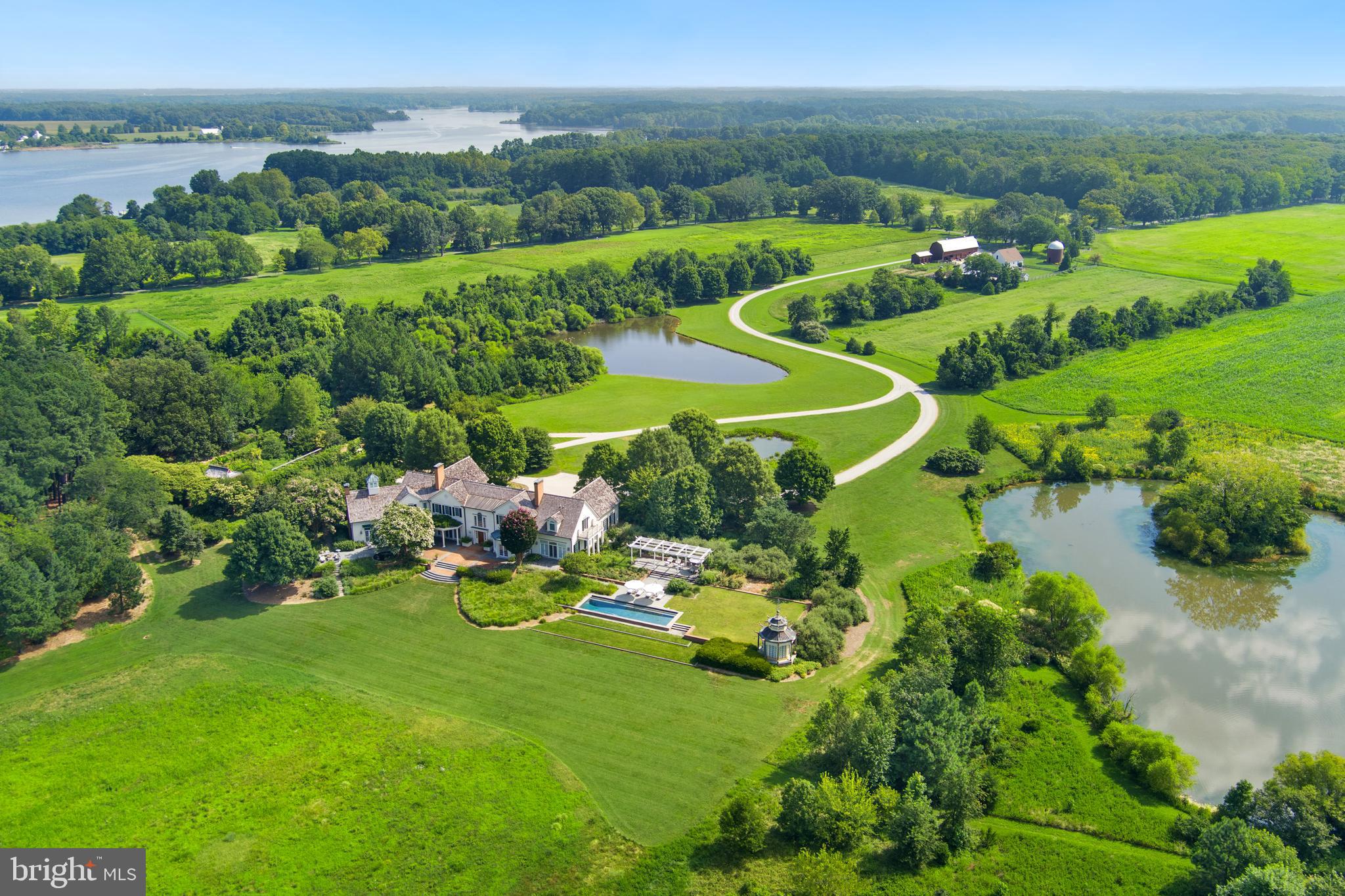 Hartwell Estate features 80 private acres with pristine, panoramic views on the mouth of the Langford and Chester River.  This light filled custom built home and property captures the essence of serene living on Maryland's Eastern Shore. One of only 4 premiere properties at the end of Quaker Neck, often called "Kent County's Gold Coast"  is sited to take advantage of the natural landscape with expansive views of the river, the owners' goal was to retain the feel and function of a working farm, but to add a modern house inspired by Maryland's historic heritage. The residence succeeds as a home for family comfort, entertaining, relaxing, gardening, hunting, fishing, birding and appreciating wildlife. Its east/west orientation highlights sunrises and sunsets that can be enjoyed from every room in the house. A real retreat.
The five bedroom and 7 fireplace (woodburning) home was designed with 12-foot ceilings on the first floor to accentuate the views and the light. A main floor primary suite includes two separate ensuite dressing rooms and bathrooms along with a wood burning fireplace. The second floor has four bedrooms, three with fireplaces, and all with ensuite bathrooms. One bedroom has a separate sitting room. A wide hall runs along the width of the house providing access to all of the rooms.
The property features the landscape design of acclaimed D.C. based Oehme, van Sweden. Hardscapes and plantings were strategically orchestrated and include a walled garden filled with flowering trees and shrubs along with a sweep of peonies in the spring. Three ponds invite active wildlife, including a beautiful blue heron. 50 acres of fields are currently being organically farmed by a neighboring farmer.  An additional 3 bedroom and 2 bath cottage (c 2012), adjacent to a barn and silo, currently occupied by a caretaker, is situated near the property entrance. Two covered structures within the walled garden provide a relaxing reading or meditation venue. Bluestone and brick terraces along the entire river facing side of the house lead to a pool and pool pagoda.
The property is uniquely designed to capture the feeling of the land while being welcoming and inviting to all who live there or visit. It has been lived in and loved by the original owner for over two decades. Family hunting and fishing are exceptional. Rock Fish is plentiful. The main residence has recently benefited from a new cedar shake roof and updated energy efficient French doors and windows throughout. The unfinished basement is approx. 2900 square feet with 9' ceilings, inviting the next steward to introduce additional lifestyle enhancements.
Less than 10 miles to downtown Chestertown, with its restaurants, coffee shops, food stores, bookstore and vibrant music and art scene, this property combines riverfront tranquility with easy access to town. 
Additional FAQ:  2013-caretaker house built; 2020 small pond redesigned and landscaped; 2021 new cedar shake roof installed, copper gutters and downspouts repaired as needed; 2022 all windows and French doors on main level replaced with top of line Anderson product- trim removed, replaced and painted; 3 lintels in walled garden replaced with black walnut; 2024 resurfaced entire lane from Lands End Road to main residence; all windows and French doors on 2nd level replaced; farm buildings painted.
Property access is restricted to scheduled appointments only.