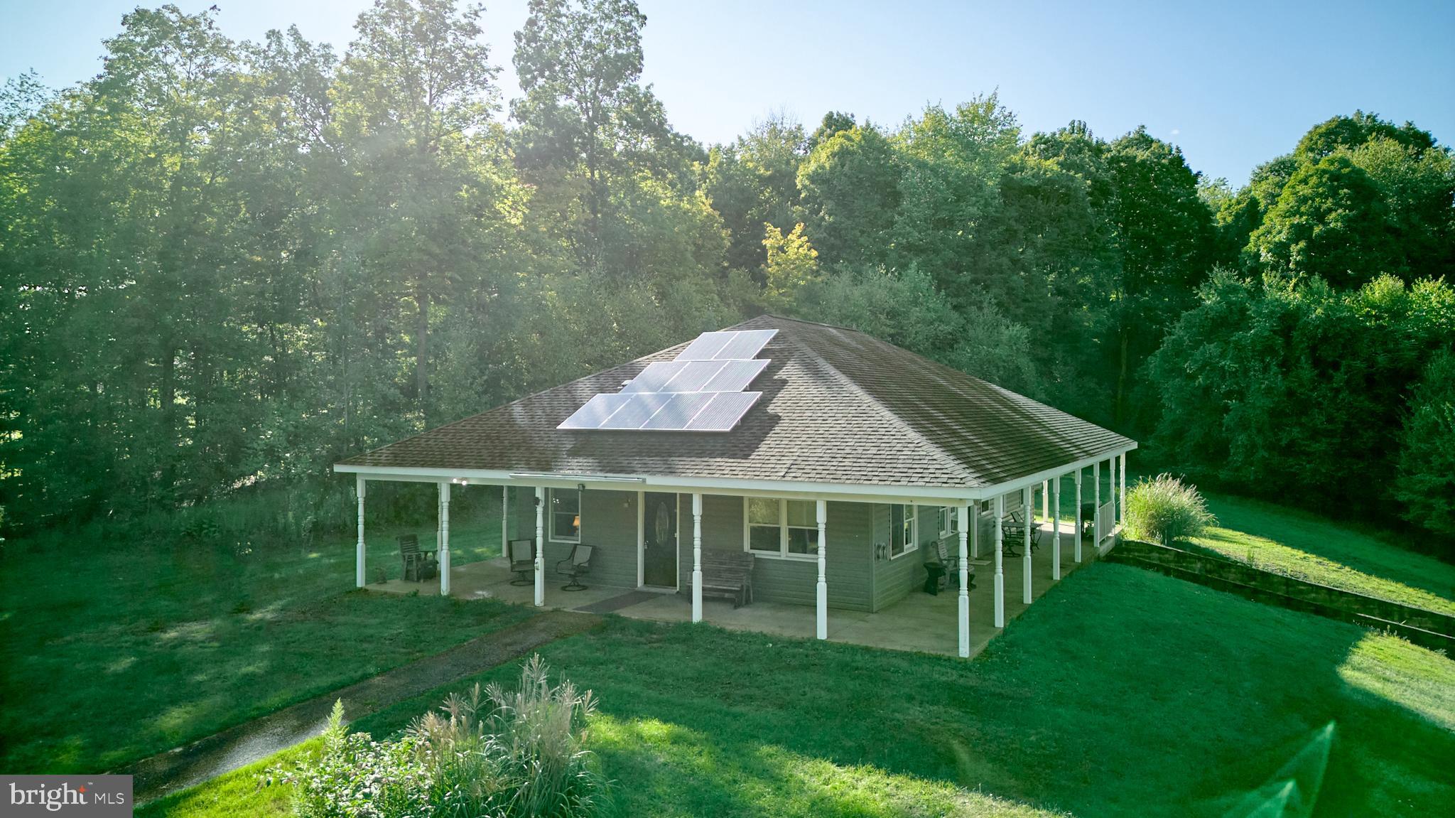 Looking for a peaceful escape? Check out this ranch home with stunning views from the wraparound porch. It includes an owner's suite, an additional bedroom, and a full bath. Nestled on 49.56 wooded acres, this off-grid property features solar panels and propane heating. The open floor plan connects the kitchen, dining, and living room seamlessly. The property also includes a 30x40 pole barn/garage. Great hunting. 15 drive to PSU and State College.