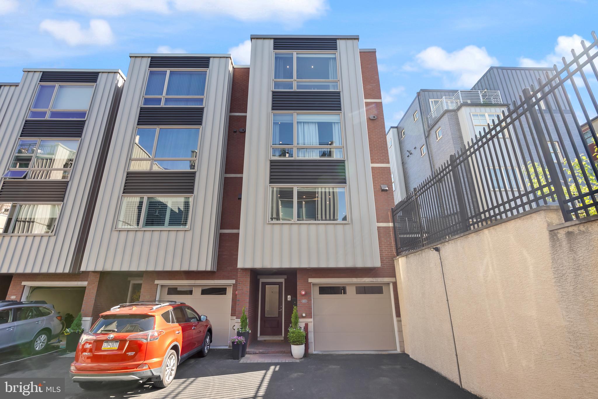 Located in the heart of Philadelphia’s highly desirable Queen Village neighborhood, this 4,300 sq. ft. luxury townhome offers refined city living within the private, gated enclave of Shot Tower Estates. Built in 2016, the home benefits from a tax abatement through the end of 2026 and provides effortless access to Philadelphia’s top hospitals, universities, tech hubs, and financial centers, all just minutes from major air and rail transportation. This beautifully appointed home sits on a desirable corner lot and spans five levels and includes 4 bedrooms, 4 full bathrooms, 1 half bath, a private 5-stop wood-paneled elevator, and two-car parking, comprised of a private garage with storage plus an additional deeded parking space located in the secure driveway (property line extends 19 feet into the driveway courtyard). The entry level features a bedroom with an attached full bath and access to a recently upgraded private rear patio (2022) with EP Henry pavers, planters, and trellises—ideal for relaxing, entertaining, or grilling. The finished lower level offers a spacious recreation room, full bathroom, and a custom wet bar, perfect for use as a gym, media room, or guest suite. The second floor is designed for entertaining, showcasing a light-filled great room with floor-to-ceiling windows, a gas fireplace with custom tile surround, and an open layout. The chef’s kitchen features Sub-Zero and Wolf appliances, custom cabinetry, and ample island seating. A powder room and private balcony complete this level. On the third floor, you’ll find two generously sized bedrooms with ample closet space, a full hall bath, a laundry room with sink and cabinetry, and an additional storage closet. The fourth floor is dedicated to the luxurious primary suite, complete with two walk-in closets outfitted with custom built-ins, a gas fireplace, integrated surround sound, and a spa-like bathroom with heated floors, double vanities, a soaking tub, and a large stone shower with multiple shower heads. The rooftop level features a pilot house with a wet bar that opens to a fiberglass roof deck (redone in 2022 with a transferable 10-year warranty), offering stunning 360° views of the city skyline, Delaware River, and bridges, with prime viewing for holiday fireworks shows. Additional highlights include whole-house audio, an alarm system with two keypads, a video intercom, and secure gated entry for guests and package delivery. The $100/month HOA covers shared utilities (gate, lighting, stormwater), common area maintenance, insurance, tree care, and snow removal. Located in the award-winning Nebinger School catchment and walkable to top local favorites like Royal Sushi Izakaya, Java Coffee, Bridget Foy’s, Capri, Lucky’s Last Chance, and Palm Tree Market, with parks, playgrounds, the Italian Market, and Headhouse Square just steps away—this home combines luxury, convenience, and community in one of Philadelphia’s most vibrant neighborhoods.