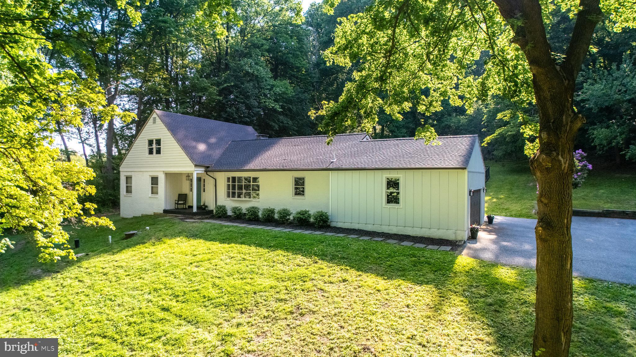 A rare opportunity to own your own private sanctuary, this spectacular park-like property offers 5 acres of peaceful woodlands and exceptional privacy. The expansive grounds provide endless possibilities for outdoor recreation, entertaining, gardening, or simply enjoying the beauty of nature. A graceful driveway winds through mature trees, creating a picturesque approach and setting the tone for everything this special property has to offer.  Step through the colorful front door into a welcoming foyer that opens to a spacious, sun-filled living room. Further down the central hall, the warm and inviting family room features a decorative fireplace and sliding glass doors that lead to the porch, seamlessly connecting indoor and outdoor living.  The kitchen offers newly tiled flooring, wood cabinetry, and a sunny breakfast area overlooking the beautiful backyard. Adjacent to the kitchen, the laundry room includes a generous pantry and provides convenient access to the attached two-car garage.  Designed for comfortable first-floor living, the well-sized primary suite features a renovated private full bath and dressing area. A large second bedroom, refreshed powder room, and spacious hall closet complete the main level.  Upstairs, you'll find two additional spacious bedrooms and a recently updated full bathroom with a tub/shower combination.  The expansive lower-level recreation room offers painted ceilings, ample lighting, a bar area, and abundant storage space—ideal for entertaining, hobbies, or game nights.  Outside, the backyard is a true retreat. Whether enjoying morning coffee, al fresco dining, or hosting festive gatherings and barbecues, the outdoor spaces provide a stunning setting. Open grassy areas, including a fenced section, are framed by mature trees that create a natural canopy and breathtaking views in every season.  Recent improvements include a new roof (2024), Hardie plank siding (2024), and new on-site septic (2016) with option to switch between old and new for longevity.  Despite its peaceful, secluded setting, the property is just minutes from shopping, Whole Foods Market, Birchrun Hills Farm, excellent dining options, and the outdoor recreation opportunities of Marsh Creek State Park