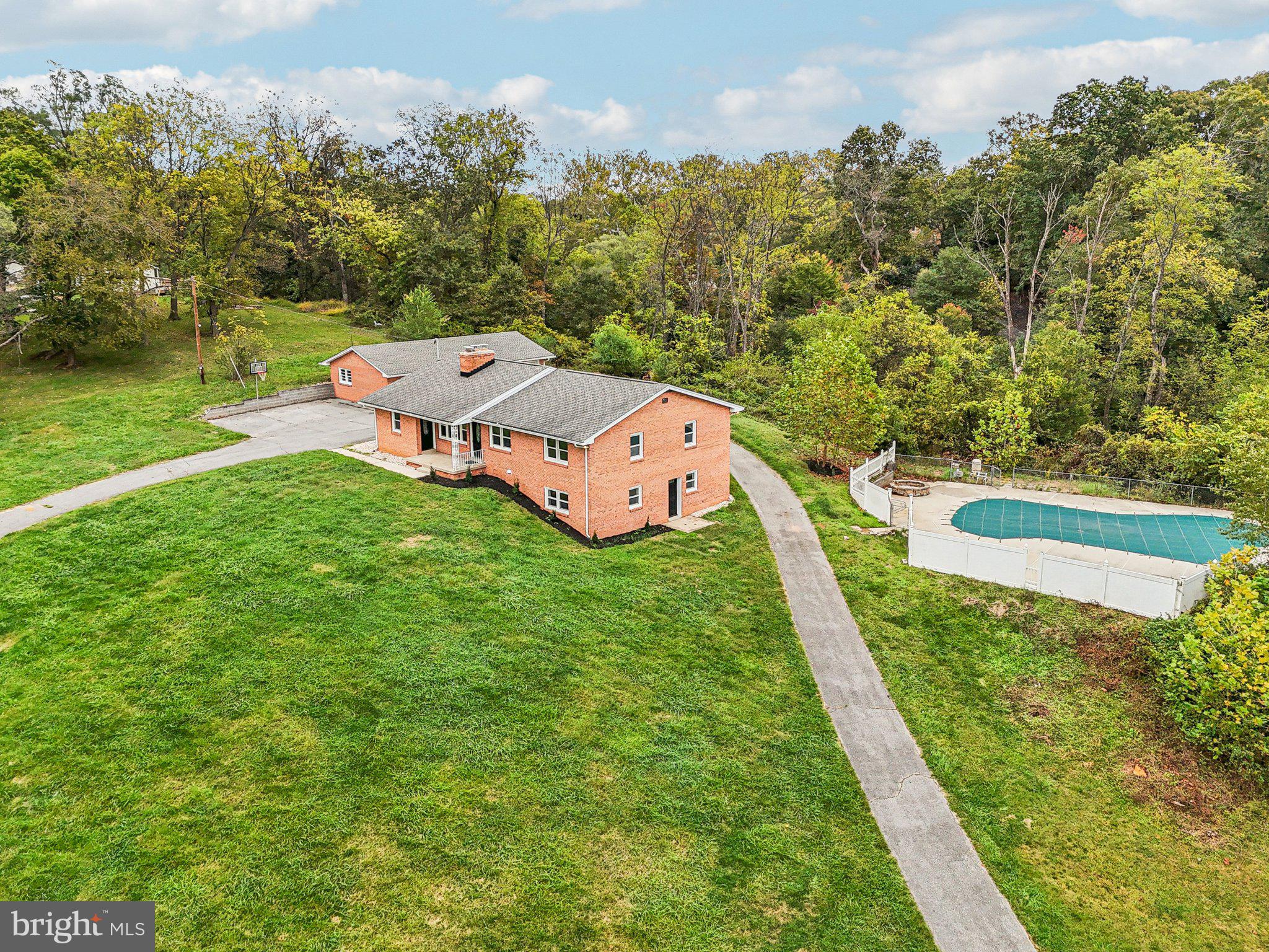 Escape to your own world with this stunning six-bedroom, three-full bath brick rancher nestled on a magnificent 5-acre lot, offering unparalleled amenities including an astro-turf sports field and a fenced-in, in-ground swimming pool. The main level showcases luxury living with refinished hardwood floors, fresh paint, and bright vinyl double-pane windows throughout. Highlights include a cozy living room with a wood-burning fireplace, a formal dining room with deck access, and a sparkling kitchen equipped with new granite countertops, stainless-steel appliances, and updated white cabinetry. The main floor also features a flexible office/den/bedroom with a separate entrance, an updated full hall bath, and a private primary bedroom retreat with an updated en-suite bath. The finished lower level dramatically expands your entertaining options with a spacious rec room featuring a second wood-burning fireplace and new LVP floors, a stylish full bath, and two large additional bedrooms with new carpet. Practicality meets luxury with a large laundry / storage room and a large circular driveway leading to a detached, expanded three-car garage. From the charming covered front porch to the convenient closed-in rear porch and deck, this property delivers unmatched space and amenities for upscale living and entertaining
