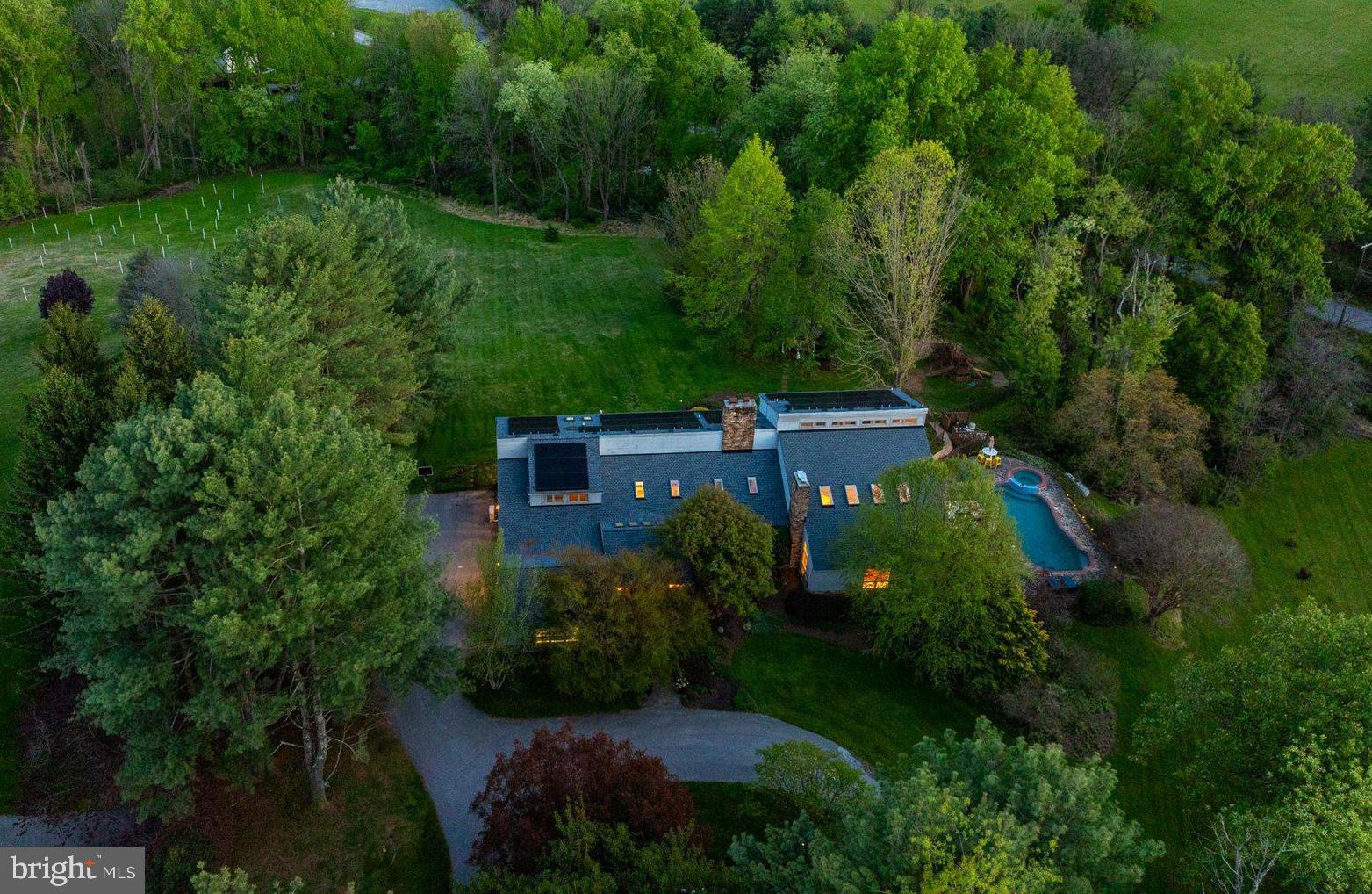 Just in time for Summer - newly listed spacious country home with pool, multiple decks and patios, salt-water hot tub, rolling lawns, and charming gazebo. The sprawling grounds are perfect for outdoor play, lacrosse practice, observing wildlife, or chasing fireflies. This striking contemporary home, set on almost four pastoral acres in Baltimore hunt country, features vaulted ceilings, skylights, floating staircases, and walls of windows. The design includes building materials that reflect the natural setting: floor-to-ceiling stacked stone walls and fireplaces, reclaimed wood beams, pine plank floors. With five bedrooms and six full baths, there is ample room to house and entertain family, friends, and guests. The vaulted primary suite has its own deck and a private bathroom that includes an oversized walk-in shower, soaking tub, dual vanity, and fireplace. Three additional bedrooms and two more full baths are spread out across this level. The finished lower level includes another full bath, bedroom, and living room - ideal for an in-law or au pair suite. Highlights on the main level include a vaulted great room with soaring ceilings, large stone fireplace, wall of built-ins, and access to the largest of several decks. The adjoining kitchen features alder cabinets, soapstone counters, stone backsplash, and stainless appliances. It adjoins an elegant dining room with pastoral views. At the far end of the main floor is a cozy library with custom cherry bookshelves - it too opens to a private deck. Near the library is a large cooking studio and office, recently created by converting two of the four garage bays into conditioned space. This space can easily be converted to an art or woodworking studio, home gym, family room, or even into separate living quarters. It has its own outside entrance, opens into the main level, and is located near a full bath. Significant improvements include a new roof (2024), all new skylights (2024), and high-efficiency solar panels (2025).  Energy savings from solar installation on this 6,000-plus-square-foot home are estimated to be over $5,000 per year - the June 1, 2026 one-month bill is only $10.32. Solar panels are owned, not leased, and transfer to the new owner.  Outside amenities are ideal for relaxing and entertaining. They include a gunite pool, six-person salt water hot tub (2025), fenced play area that doubles as a dog run, gazebo, and outdoor space for sport and exploration. There is ample room for vehicles with a two-car garage, parking area, and circular driveway. Enjoy lush landscaping, rolling hills, and the peace and quiet of country living just minutes from Hunt Valley Towne Center, the NCR Trail, Worthington Valley biking, and Oregon Ridge Park. See interactive floor plans and property video. Details on roof, skylights, and solar provided.