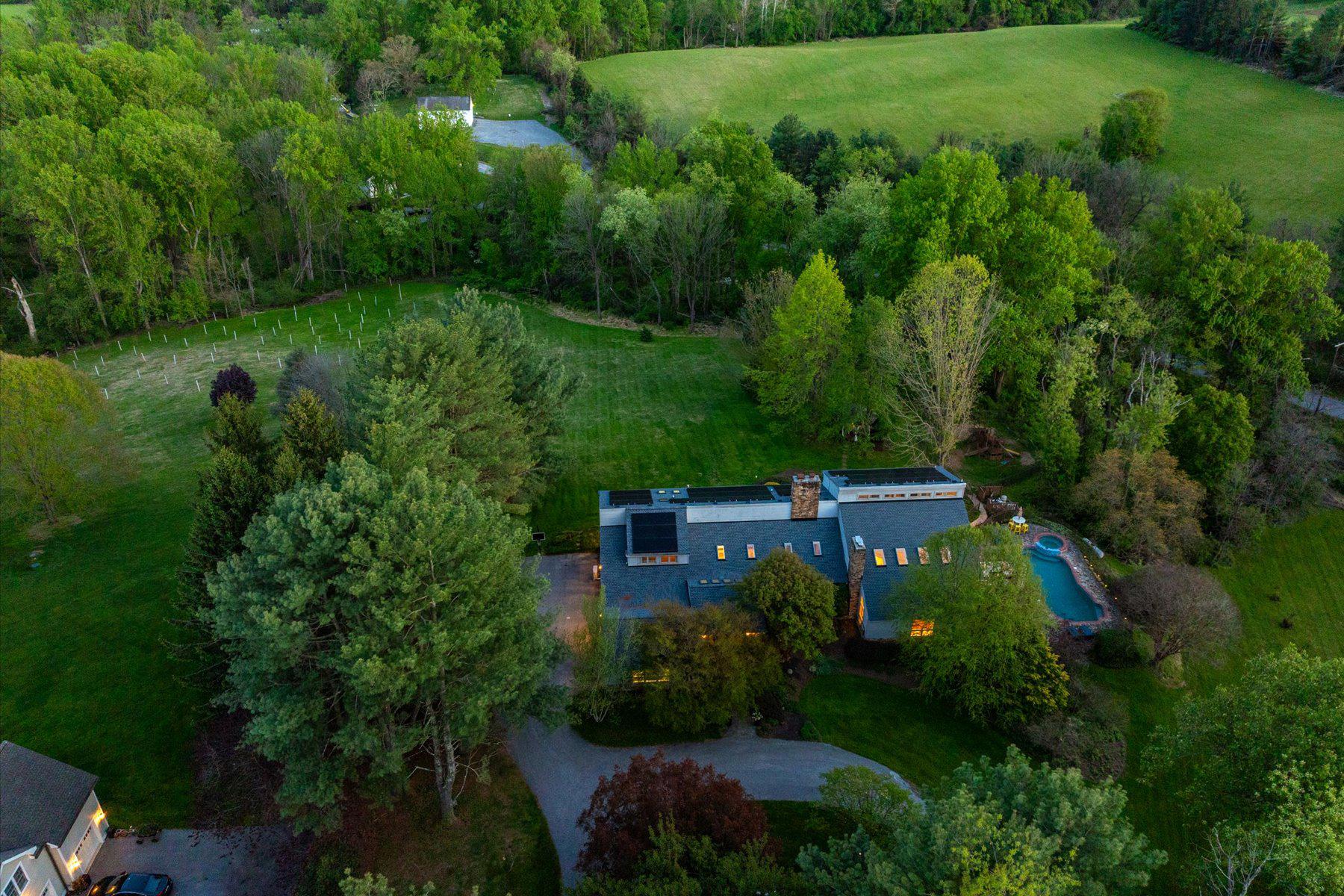 Just in time for Summer - newly listed spacious country home with pool, multiple decks and patios, salt-water hot tub, rolling lawns, and charming gazebo. The sprawling grounds are perfect for outdoor play, lacrosse practice, observing wildlife, or chasing fireflies. This striking contemporary home, set on almost four pastoral acres in Baltimore hunt country, features vaulted ceilings, skylights, floating staircases, and walls of windows. The design includes building materials that reflect the natural setting: floor-to-ceiling stacked stone walls and fireplaces, reclaimed wood beams, pine plank floors. With five bedrooms and six full baths, there is ample room to house and entertain family, friends, and guests. The vaulted primary suite has its own deck and a private bathroom that includes an oversized walk-in shower, soaking tub, dual vanity, and fireplace. Three additional bedrooms and two more full baths are spread out across this level. The finished lower level includes another full bath, bedroom, and living room - ideal for an in-law or au pair suite. Highlights on the main level include a vaulted great room with soaring ceilings, large stone fireplace, wall of built-ins, and access to the largest of several decks. The adjoining kitchen features alder cabinets, soapstone counters, stone backsplash, and stainless appliances. It adjoins an elegant dining room with pastoral views. At the far end of the main floor is a cozy library with custom cherry bookshelves - it too opens to a private deck. Near the library is a large cooking studio and office, recently created by converting two of the four garage bays into conditioned space. This space can easily be converted to an art or woodworking studio, home gym, family room, or even into separate living quarters. It has its own outside entrance, opens into the main level, and is located near a full bath. Significant improvements include a new roof (2024), all new skylights (2024), and high-efficiency solar panels (2025).  Energy savings from solar installation on this 6,000-plus-square-foot home are estimated to be over $5,000 per year - the June 1, 2026 one-month bill is only $10.32. Solar panels are owned, not leased, and transfer to the new owner.  Outside amenities are ideal for relaxing and entertaining. They include a gunite pool, six-person salt water hot tub (2025), fenced play area that doubles as a dog run, gazebo, and outdoor space for sport and exploration. There is ample room for vehicles with a two-car garage, parking area, and circular driveway. Enjoy lush landscaping, rolling hills, and the peace and quiet of country living just minutes from Hunt Valley Towne Center, the NCR Trail, Worthington Valley biking, and Oregon Ridge Park. See interactive floor plans and property video. Details on roof, skylights, and solar provided.