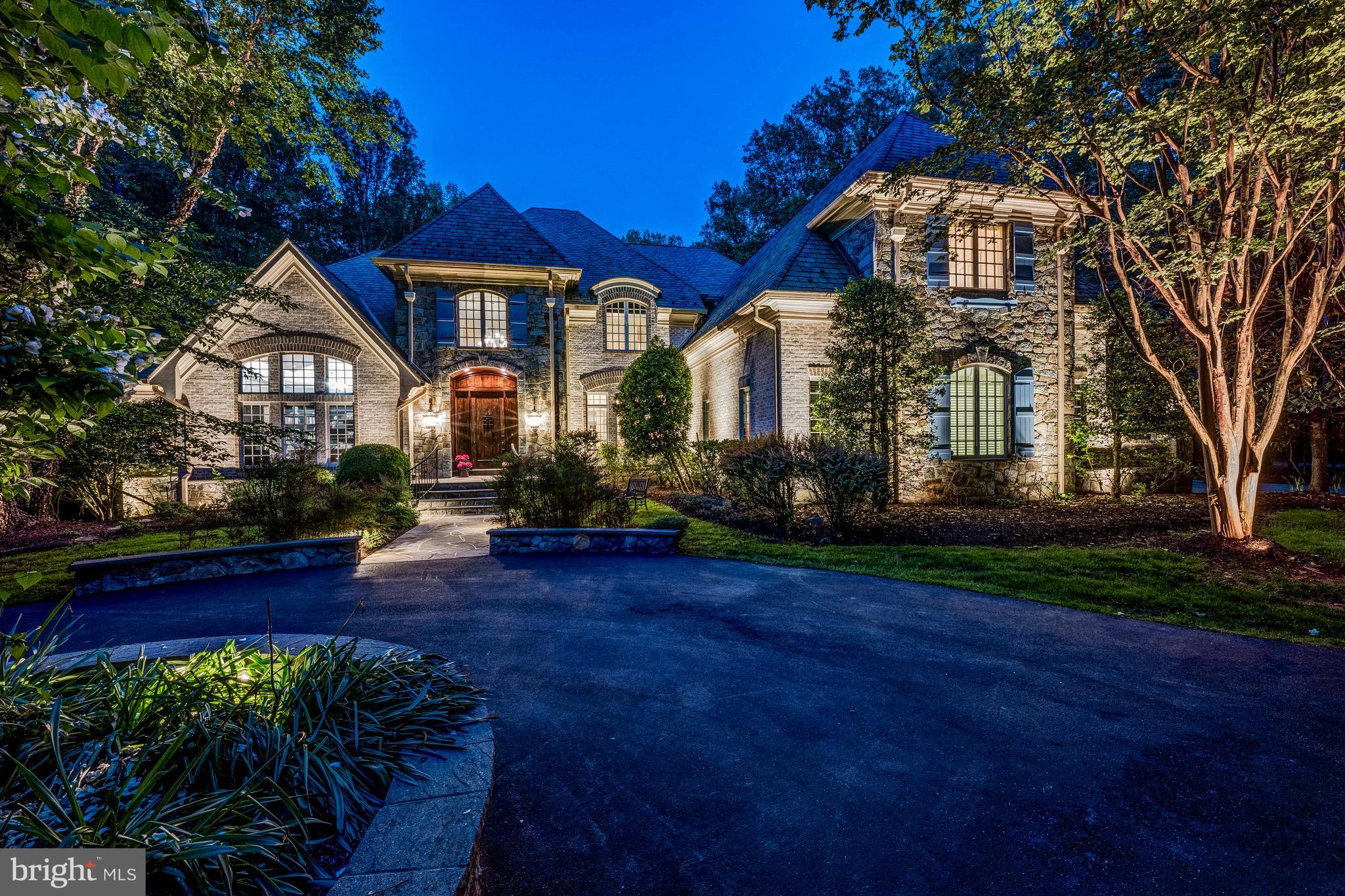 Welcome to this exquisite French Country estate, custom built and perfectly situated on 3.5 private, beautifully landscaped acres. A grand circular driveway sets the tone as you arrive at this elegant retreat. Step inside to a dramatic two-story foyer with a sweeping curved staircase, leading into a breathtaking great room featuring soaring ceilings, floor-to-ceiling windows, and a stunning custom fireplace mantel. The spacious formal dining room connects to a well-appointed butler’s pantry with custom cabinetry and a wine fridge. The chef’s kitchen is a true centerpiece, outfitted with top-of-the-line appliances, a generous center island, bar seating, and a cozy breakfast room. The kitchen flows seamlessly into the two-story family room, showcasing a vaulted, beamed wood ceiling, stone fireplace, and custom built-ins. The main-level owner's suite offers a privacy with vaulted ceilings, a fireplace, morning bar with beverage chiller, and a luxurious spa-inspired bath. Enjoy a jetted soaking tub, a walk-in shower with multiple body sprays, dual vanities, and two expansive walk-in closets with custom built-ins. Upstairs, a charming loft overlooks the family room and provides access to three private en-suite bedrooms and the laundry room. The walk-out lower level is designed for both relaxation and entertaining. You're welcomed by a striking stone niche accent wall, setting the tone for the exceptional spaces ahead, including a wine tasting room, a spacious recreation room with adjoining kitchenette, and a billiard room with a stone fireplace. A fitness room and a beautifully designed spa bath complete this level. Outside, enjoy an expansive deck overlooking the serene, tree-lined grounds, with stairs leading down to a spacious, flat backyard.