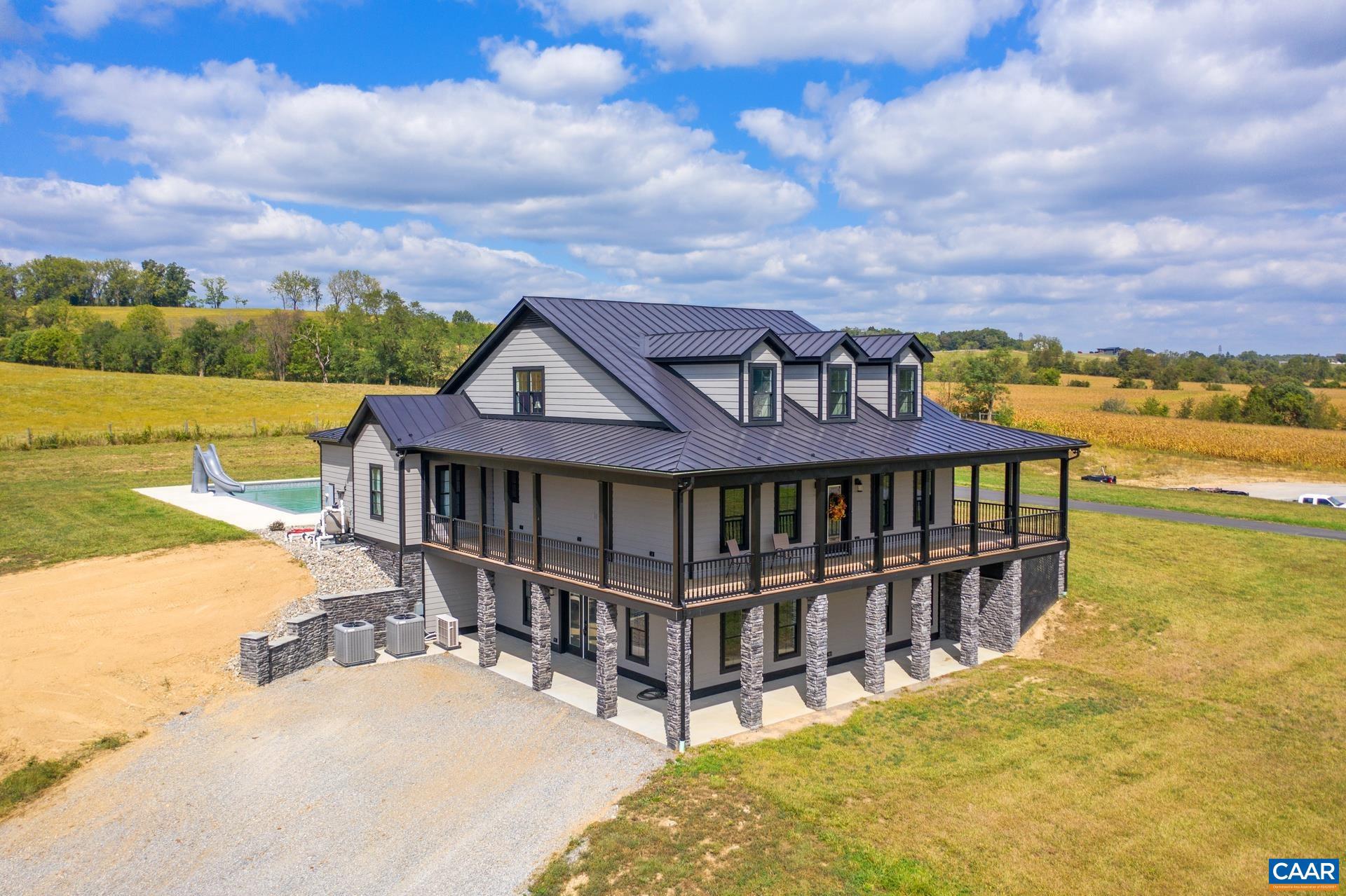 Beautiful panoramic mountain views await you! Conveniently located near Rt. 250 and Rt. 254, with fiber internet available.  Perched on a hill in a mostly private setting, you will love looking at the mountains while sitting on the large covered front porch or swimming in the L-shaped pool. The kitchen features a gas range, farmhouse sink, an island,  granite countertops with plenty of workspace, and white cabinetry.  Enjoy mountain views from the dining room and the living room. The primary suite features dual walk-in closets, double vanities with cabinetry, and an 11' X 5' tiled shower with two shower heads. The utility room just off of the 3-car garage and pool area doubles as a laundry area and a pool room.  The utility area includes a bathroom with a shower that can also be used as a dog washing station.  The unfinished basement includes roughed in plumbing and a mostly finished safe room.  The property also features a 6,000 sf detached garage/workshop, with a half bath.  Detached garage includes 6 garage bays.  The home and garage/workshop have standing seam metal roofs. Whether you are at the pool, the pond, or sitting on one of the many porches and patios, you will love the beauty all around you!,Granite Counter,White Cabinets,Fireplace in Living Room