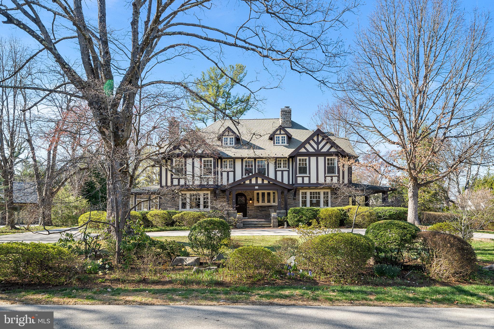 Welcome to a rare and remarkable offering—a stately Tudor masterpiece designed by the renowned Philadelphia architectural firm Duhring, Okie & Ziegler. Built in 1912, this distinguished residence embodies classic Main Line elegance while seamlessly integrating modern conveniences. Nestled on nearly an acre on the coveted north side of Haverford, this home boasts almost 6,000 sq. ft. of timeless sophistication.

Approached via a sweeping circular driveway, the home’s stone exterior, accented with weathered finishes, exudes old-world charm. Enter through the grand foyer, complete with formal powder room, where wide-plank wood floors, deep window sills, and hand-hewn beams set a refined tone. A striking fireplace, one of four throughout the home, enhances the warm and inviting ambiance. To the right, the richly appointed library features built-in bookcases, a second fireplace with a brick surround and white wood mantel, and French doors leading to a covered side porch. The adjacent living room/family room offers additional gathering space, connecting effortlessly back to the foyer. To the left, the sun-drenched formal dining room leads to a cozy carpeted family room with exposed stone and access to another covered porch. The adjacent butler’s pantry serves as a passage to the gourmet kitchen, exquisitely remodeled by EB Mahoney. Designed for culinary excellence, it features Wood Mode custom cabinetry, granite countertops, recessed lighting, a Thermador five-burner gas cooktop on the island, a Dacor double oven, and a Bosch dishwasher. A mudroom and powder room provide convenient access to the driveway, rounding out the first floor.

Ascend the grand staircase to the second level, where the primary suite offers a serene retreat with an ensuite bath. A second bedroom, currently utilized as a den/office, boasts custom built-ins. The third bedroom, newly carpeted, connects to a recently upgraded Jack & Jill bathroom leading to the fourth bedroom. The fifth bedroom features a beautifully remodeled ensuite bath with a frameless shower door and ample closet space. Nearby, a well-appointed laundry area with LG appliances and additional storage sits adjacent to a back staircase leading to the kitchen. Completing this level is the enchanting sleeping porch—a versatile space perfect for a yoga room, gym, home office, or recreation area. The panoramic windows frame picturesque views of the pool, patio, and lush backyard.

The third level is a haven of possibilities, offering five additional rooms with hardwood flooring throughout. Ideal for guest accommodations, office space, a gym, or a homework area, this level also includes a full bathroom, built-in cedar drawers, closets, and extensive storage areas. The unfinished walk-out basement provides abundant storage and further opportunities for customization.

The beautifully landscaped grounds are a true highlight, featuring mature plantings such as azaleas, oak leaf hydrangeas, and dogwoods. The inviting pool, framed by vibrant roses and lush greenery, offers a serene escape. Raised garden beds, a potting shed, and a private backyard add to the charm. A detached two-car garage includes an unfinished space above, presenting potential for a guest cottage or private studio.

Situated in close proximity to Bryn Mawr and Haverford Train Stations, as well as several prestigious private schools and renowned universities, this exceptional home offers both tranquility and convenience. Experience the unparalleled character and grandeur of this magnificent Main Line residence—a home that promises timeless elegance and gracious living.