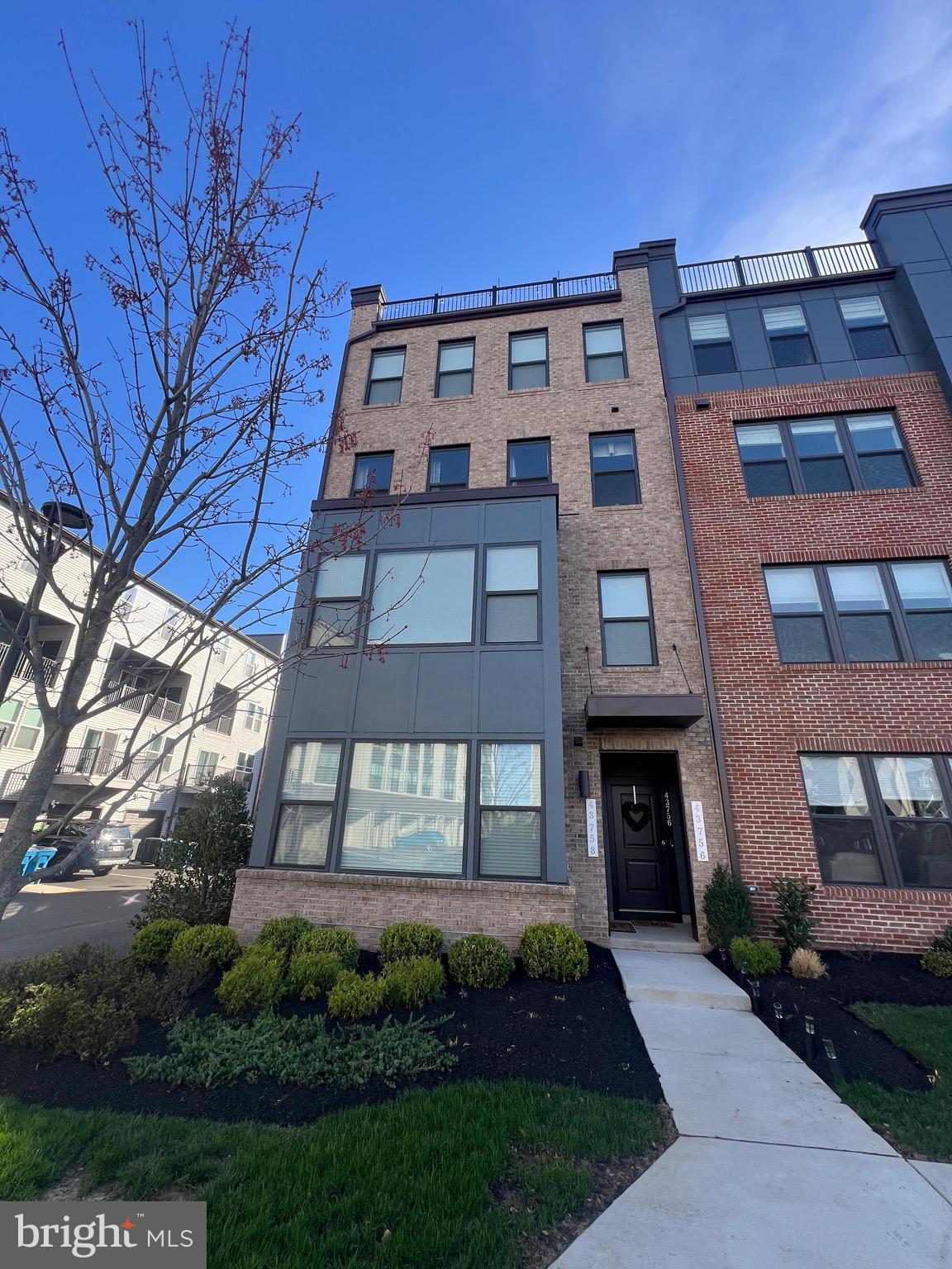 This modern multi-level home—originally a designer model unit converted into a private residence in 2024—features three bedrooms and 2.5 bathrooms, including a third-floor master suite with a custom walk-in closet and private bath. The layout is designed for convenience, placing the laundry room on the bedroom level, while the second floor offers a spacious living room, kitchen, dining area, office, and pantry, all accented by custom-designed feature walls and a private balcony. The ground floor provides dual entry points through the front door or the garage, which comes equipped with a 240V electric vehicle charging outlet and additional driveway parking. For entertaining, the fourth floor boasts a rooftop patio for social events, complemented by a central camera security system throughout all levels and an outdoor picnic area. Also, there are "blackout" blinds installed fitted with the necessary electricals.  Perfectly situated for commuters, the property is just three minutes from the Ashburn Silver Line Metro station and ten minutes from Dulles International Airport, with the option to purchase the home fully furnished.
