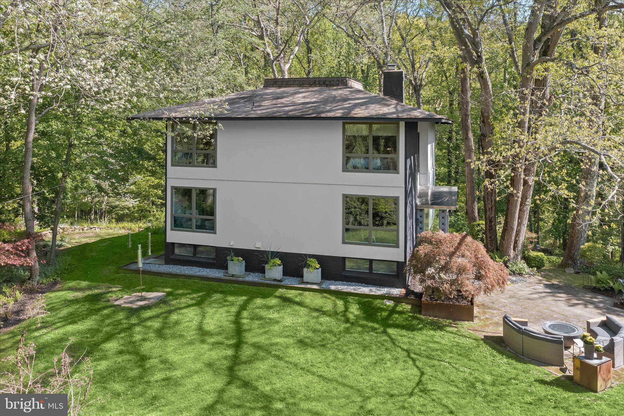 Imagine living in a private woodland retreat where architecture, nature, and creativity converge. Set on nearly four serene acres in Carroll County, this architecturally distinctive residence thoughtfully designed by artist/designer couple and owners Julie and Ken Girardini offers a peaceful setting with a gentle stream winding through a mature forest, in addition to curated gardens, and a greenhouse for year-round growing.  A memorable approach begins along a wisteria-covered walkway leading to a tranquil koi pond, fountain, and Japanese rock garden, setting the tone for the artistry woven throughout the property.

Inside the main residence, a bright open floor plan is enhanced by dramatic corner windows, including Andersen awning windows with fixed upper panels and Andersen sliders, which frame the landscape and fill the home with natural light. Oak hardwood flooring and calming interior tones flow throughout. 

A striking floating staircase with solid cherry treads and a steel monorail design accented by a copper handrail serves as a sculptural focal point. Artistic elements continue in the living room, where a one-of-a-kind gas fireplace clad in steel and a custom concrete relief artwork enhance the space. The living room boasts a wall of windows and dual sliders providing access to the deck. A distinctive curved steel door leads to the powder room, adding another layer of architectural interest.

At the heart of the home, the gourmet kitchen is designed for both everyday living and entertaining, featuring a gas cooktop, stainless-steel appliances, sleek custom European cabinetry, and a dedicated scullery for additional prep and storage. The dining area overlooks the open-concept layout, enhancing both flow and function.

The upper level offers a spacious primary suite with a spa-like bath and custom handmade cherry cabinetry, plus three additional bedrooms and a full bath. A full basement provides flexibility with ample storage and future finishing potential. The home is equipped with geothermal heating and air conditioning, an eco-friendly and cost-effective solution for year-round comfort.

This home exceeds expectations in quality and attention to detail, with many creative features the artist couple handcrafted in their studio. Every aspect of the property is carefully curated with a keen eye for visual harmony from every angle.

Outdoor living is equally inviting, with an expansive deck overlooking the woods, a hot tub for relaxation, and a welcoming front terrace with a gas fire pit perfect for gathering and enjoying the natural surroundings in every season.

A defining feature of this exceptional offering is the expansive 3,000-square-foot detached studio: an extraordinary live/work space designed with scale and flexibility in mind. Fully heated and air-conditioned, the structure includes a 12' × 9’ high bay door and an attached two-car garage.  A car enthusiast dream!  The space is equipped with an air compressor and airline connections throughout multiple workshop areas, plus a powder room. The upper level hosts a  private office/gallery with its own high-speed Wi Fi connection, while the lower level features two sliding doors providing walkout access to the greenhouse, seamlessly blending workspace with the natural surroundings. With soaring 10-foot ceilings and abundant light, this versatile building is ideally suited for a home-based business, creative studio, workshop, or entrepreneurial venture.

This one-of-a-kind offering presents a rare opportunity to enjoy privacy, tranquility, natural beauty, and a highly functional live/work lifestyle all within convenient reach of everyday amenities.