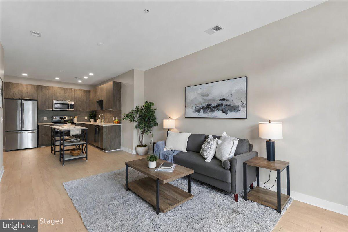 Gorgeous 1-bedroom, 1-bathroom condo in the sought-after Trafalgar Flats condominium, built in 2019! This light-filled home offers stylish finishes, an open layout, one assigned parking space that conveys (#18) & an unbeatable Arlington location close to shopping, dining, & outdoor recreation. The welcoming entry features a convenient coat closet & opens to the bright main living area showcasing stunning wood-look flooring throughout. The contemporary kitchen boasts gray soft-close cabinetry, stone countertops, a gray subway tile backsplash, stainless steel appliances, recessed lighting, & abundant storage. The spacious living room offers plenty of room for relaxing or entertaining, along with a sliding glass door that opens to the charming Juliet balcony.

The generously sized bedroom features plush carpeting, a modern ceiling fan with overhead lighting, & a large walk-in closet. The en-suite bathroom is beautifully appointed with oversized tile flooring, a floating white vanity, a large medicine cabinet mirror providing exceptional storage, & a tiled shower with a deep soaking tub. A laundry closet with a stacked washer & dryer completes the home.

Residents of Trafalgar Flats enjoy a host of amenities, including a fitness center, bike storage room, a community patio with two gas grills & a fire pit, plus a fenced dog relief area. A new gym is also expected to begin construction this summer. With a low condo fee, bus access just steps away, the W&OD Trail nearby, & walkable access to restaurants, shops, & grocery stores, this exceptional home offers the perfect blend of convenience, comfort, & modern living.