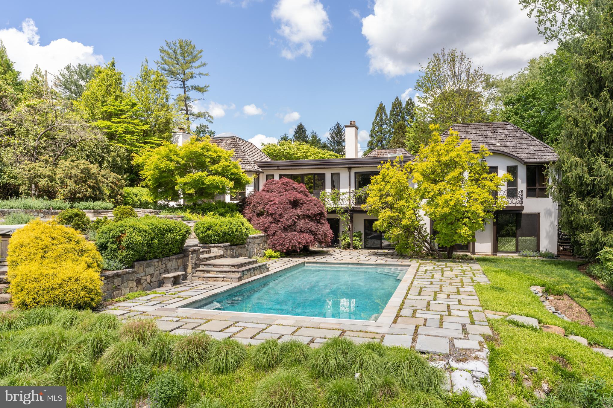 This contemporary and elegant house on two acres features designer finishes with the original interior design by Solis Betancourt. There is phenomenal attention to detail in every room of the five bedroom and five and a half bath main house. The open floor plan architecture maximizes natural light with skylights and French doors overlooking the multi tiered gardens and stunning pool. Passing under the pergola with Wisteria vine you enter the house to the formal entry hall. The main level features a formal dining room, a cathedral ceiling living room with skylight and fireplace. The modern eat-in kitchen features Miele appliances and a pantry with wine refrigerators. The stunning master suite has an office with fireplace and large walk-in closet. The two other bedrooms on the main level have ensuite baths. The lower level has sliding  glass doors that open to the pool. There is a large media/family room and a large multi purpose room that can  be used a gym family room. A bedroom, two full bathrooms, a wine cellar, large laundry room and garage complete the lower level. The professionally landscaped grounds feature tiered flagstone terraces that lead to the pool with flagstone hardscape. Finally, the guest cottage features an open floor plan with skylight and a full bathroom. Truly a stunning property.