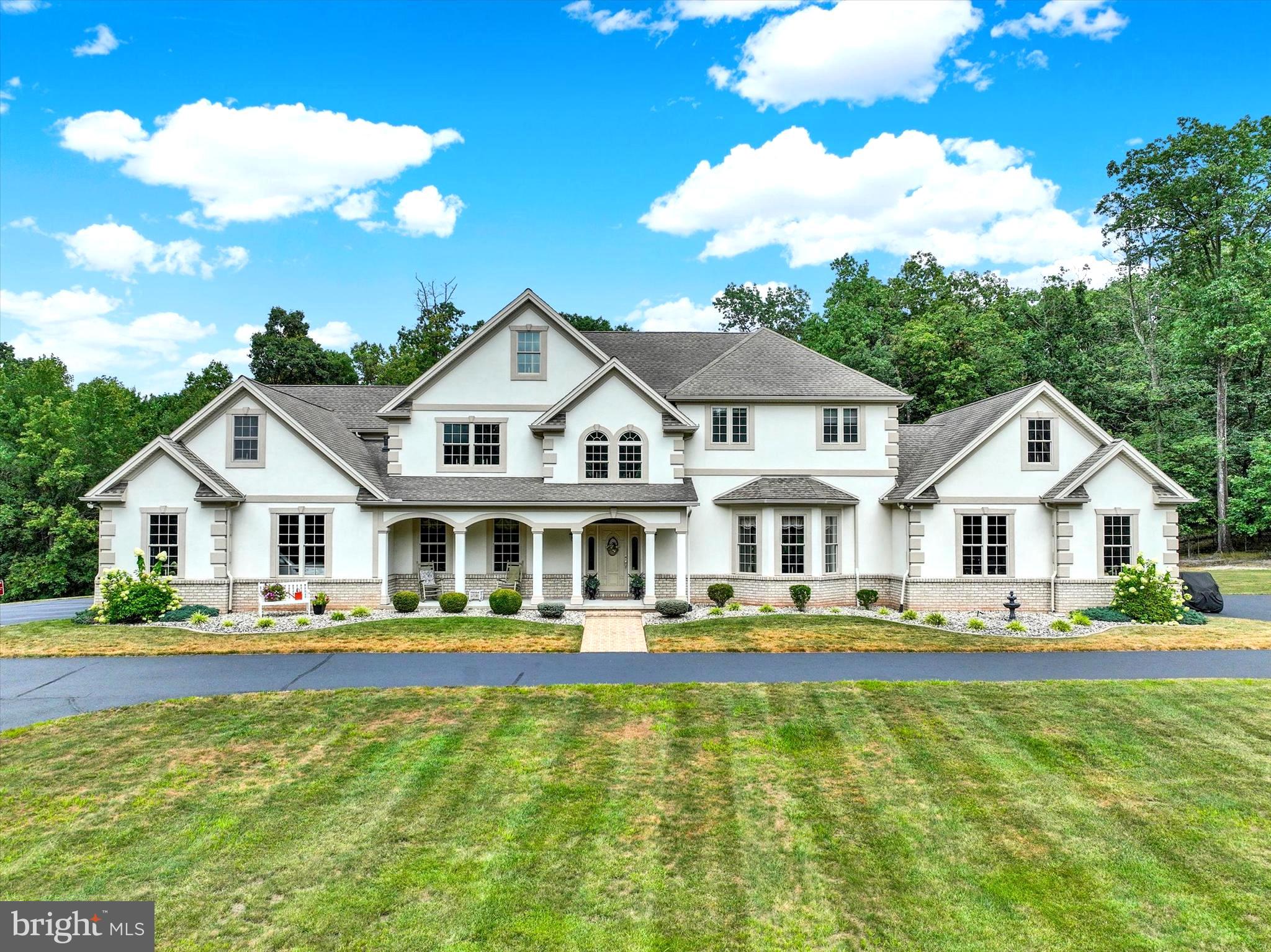 Welcome to a residence of timeless elegance and distinction. This extraordinary custom-built estate boasts over 6,000 square feet of refined living space, gracefully positioned on 58 acres of pristine, scenic countryside. A true sanctuary, the property evokes the feeling of a private resort—an enchanting retreat where luxury meets tranquility. While offering unmatched privacy, the estate is ideally located within easy reach of York, Harrisburg, Lancaster, and Gettysburg, with the Maryland line just 20 minutes away. 
The experience begins the moment you travel up the stately, tree-lined drive, leading you toward a sense of anticipation. As the driveway opens, a magnificent estate reveals itself—an architectural masterpiece set amidst a private sanctuary of unmatched beauty. Impeccably manicured grounds frame the residence, offering a breathtaking backdrop that is both serene and inviting. On warm days, an exquisite inground pool provides the perfect retreat, while at night, you can float under a canopy of stars, surrounded by the tranquility and elegance of this exceptional property. Picture a peaceful Saturday morning with coffee in hand, listening to the gentle sounds of nature, and savoring the unparalleled sense of serenity this remarkable estate affords.
Designed with both elegance and functionality in mind, this distinguished residence features two attached two-car garages, artfully positioned at each end of the home to enhance its architectural grandeur. A generously sized cement parking area offers the ideal space for campers, boats or work trailers.
This extraordinary residence reveals itself as a masterpiece of timeless design and modern elegance Spanning across three levels of finished living space. This exquisite estate offers 4 bedrooms, 3 full baths, and 2 half baths which seamlessly blends sophistication with comfort across three thoughtfully designed levels. A grand two-story foyer sets the tone with its sweeping staircase, intricate wainscoting, and streams of natural light cascading through dramatic transom windows. Formal entertaining is elevated in the distinguished dining room, where a tray ceiling, refined crown molding, and a stately fireplace create an ambiance of warmth and grace. The expansive living room, crowned with a coffered ceiling and framed by walls of windows, invites both intimate gatherings and grand entertaining, its fireplace providing the perfect centerpiece. At the heart of the home, the gourmet kitchen is a culinary sanctuary, offering bespoke cabinetry, professional-grade appliances, and an oversized island designed for both function and beauty. A sun-drenched breakfast room opens onto the terrace, blending indoor and outdoor living with effortless elegance. A main-level powder room and expansive laundry/mudroom enhance the home’s thoughtful design. Ascending upstairs, the primary suite redefines luxury living. A private sitting area, its own fireplace, and French doors to a secluded balcony create a serene retreat. This luxurious suite is enhanced by 2 full baths: his and her full bathrooms, each with their own walk-in closet, ensuring comfort, privacy, and sophistication. Additional bedrooms are generously sized and supported by well-appointed bathrooms, offering both style and practicality. The lower level extends the home’s lifestyle amenities with multiple versatile living spaces, ideal for recreation, fitness, or gatherings. A handsome fireplace adds ambiance, while a stylish half bath completes the space. The dedicated fitness room may also serve as the perfect home office or private study, offering flexibility to meet the needs of today’s lifestyle.
In total, this exceptional estate offers four fireplaces — in the living room, dining room, primary suite, and lower level — infusing warmth and sophistication throughout. Every detail, from the custom millwork to the expansive windows and architectural artistry, speaks to the home’s uncompromising quality.