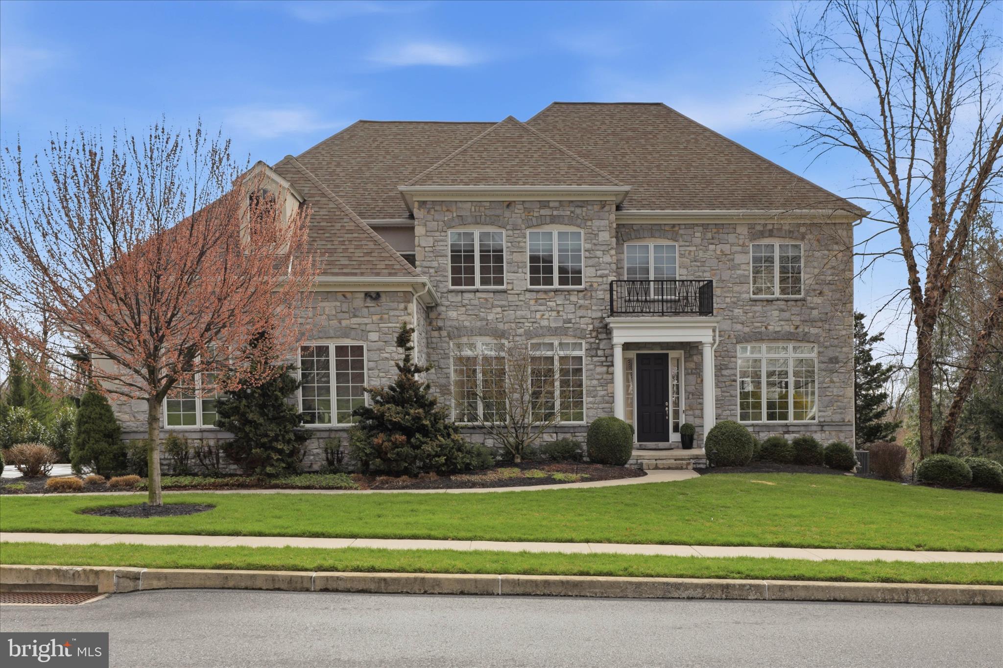 Commanding from the moment you arrive, this stunning stone-front colonial offers over 6,100 square feet of beautifully finished living space across three levels, perfectly designed for both elegant entertaining and comfortable everyday living. Set on a manicured lot with professional landscaping, a sweeping driveway, and an eye-catching stone and stucco exterior, this home makes a lasting first impression.
The Main Floor is an entertainer's dream. A grand foyer welcomes you with rich Brazilian cherry hardwood floors that flow throughout the main level. The spacious family room features a coffered ceiling, a gas fireplace with tile surround, and an abundance of natural light. The chef's kitchen is appointed with rich dark Cherry cabinetry, granite countertops, a six-burner KitchenAid gas cooktop, a stunning stacked-stone backsplash, and ample prep space — all designed for the serious cook. A formal dining room, elegant formal living room, and sophisticated library with custom-built-in floor-to-ceiling shelving round out the main level, along with a convenient butler's pantry and a dedicated laundry studio.
The Second Floor hosts five generously sized bedrooms and three full baths. The private primary suite is a true retreat, complete with a spacious walk-in closet and a spa-inspired en suite bath featuring a soaking tub, separate shower, and double vanity. The remaining bedrooms are thoughtfully connected via Jack-and-Jill bath configurations, providing comfort and privacy for family and guests alike. A beautiful open loft hallway overlooking the main level adds to the home's airy, open feel.
The Lower Level is the crown jewel — a fully finished walkout basement spanning nearly 1,500 square feet of impressive entertainment space. The showpiece wet bar features granite countertops, dark custom cabinetry, a wine cooler, a beverage refrigerator, and a bar island with pendant lighting — everything you need for hosting in style. The open recreation area flows effortlessly into a dedicated home theater/movie room. You can also get your workout in the gym or the optional sixth bedroom. The basement also features a full bath and generous storage spaces. Walkout access connects directly to the covered patio below.
Outside, the two-level outdoor living space is equally impressive. A composite deck with white railing off the main floor is perfect for al fresco dining, while the covered patio below offers a shaded retreat with a stamped concrete patio, accessible directly from the walkout basement. The professionally landscaped yard with stone retaining walls and in-ground lighting creates a private, resort-like setting. The oversized three-car garage with arched stone accents and built-in storage completes the package. This home is ideal for buyers searching for a large luxury home in the Cumberland Valley School District with a finished basement, home theater, outdoor living space, and 3-car garage.