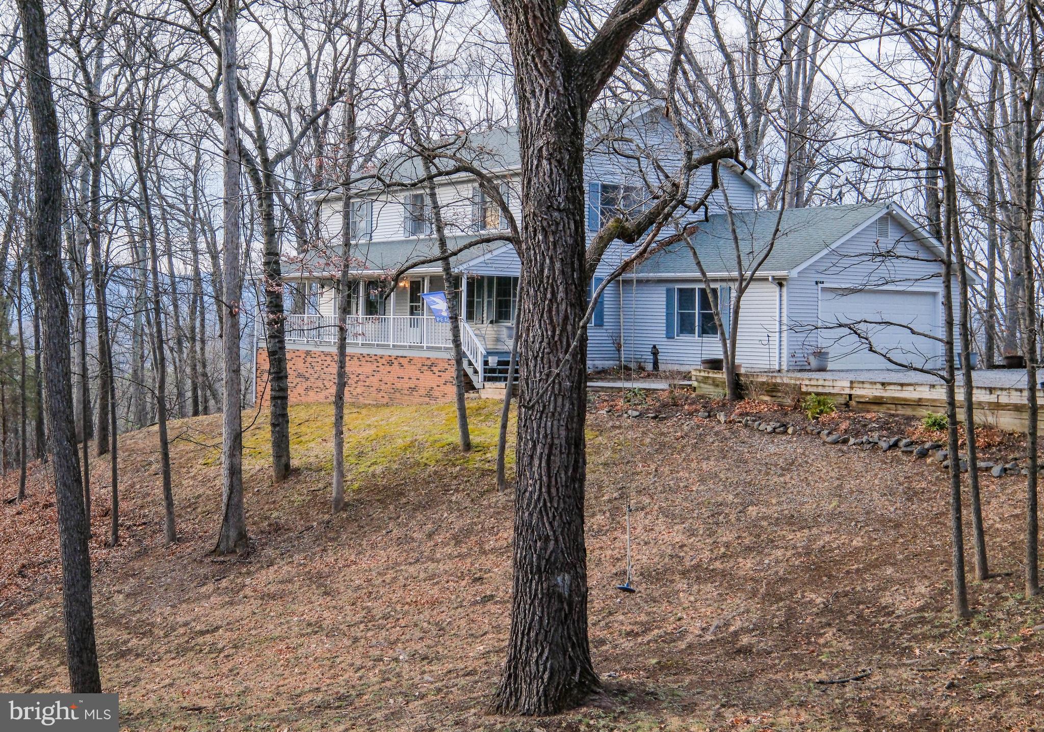 This nearly 2,400 sf remarkably PRIVATE & PEACEFUL four bedroom “treehouse” (with 2 car garage and full unfinished walkout basement offering a potential 1,100+ finished sf) is situated on 5 VIEW-FILLED acres (Shenandoah River and Blue Ridge Mountain views from nearly every window). This setting truly feels like a fairy tale and it is no wonder why the seller calls the property her “treehouse” (she custom built it to capitalize on views and privacy yet provide easy access).   <br><br>
Located just 1 mile down Browntown Road, the nicely paved little-known Cardinal Wind Drive (yes, birdwatchers will delight) boasts only two houses (the other home is at the far end and can’t be seen) and is tucked at the base of the Shenandoah National Park with nature as its neighbor. This property is approximately 3 MILES FROM EVERYWHERE (Shen River access, shopping, schools, historic downtown Front Royal, Eastham river trails/playground/dog park, library) and 8 easy miles from I-66 exit 13 (Linden). No need to drive up a mountain or 20 minutes outside of town to access this home!  And no need to spend hours every weekend on a lawn tractor! This tree-filled property still offers several delightful mossy yard areas (to include a spot with a delightful tree swing) and spectacular sunsets from the 24x12 rear deck (that has extra wide steps that lead to a walkway to the generous parking area off the lovely driveway.  <br><br>
FANTASTIC FLOORPLAN–enjoy the 42 foot long front porch (with swing), the gigantic formal living and dining rooms, the view-filled family room off the huge kitchen, the spacious main and upper foyers (main level has a half bathroom off center hallway), the 4 bedrooms/2 huge bathrooms on the upper level, the roomy laundry/mud room (with pantry and utility sink) off the kitchen and garage.  VIEWS FROM ALL ROOMS! The primary bedroom offers a large owner’s bathroom area.  The second oversized bedroom has convenient access to the fourth bedroom (would make a great home office).  <br><br>
FEATURES TO NOTE: Brick fireplace (converted to propane w/blower for added heat), Rough in plumbing in basement for a future full bathroom, Conveying washer/dryer, Storm door from garage to house, Pull-down attic steps w/ flooring and fan, Storage under deck, Conventional septic, High speed internet, Deep closets, Hardwood floors (living room, dining room, staircase), Attractive plank flooring in family room/kitchen/foyers, Corian counters (added in 2017), 4-person breakfast bar, Pull-out cabinetry, Built in desk area in kitchen, Picture window w/winter views of river, Ceiling fans (in 3 bedrooms, family and living rooms), Chair railing, Double sinks in huge hall bath (that also has a built in seated makeup area and linen closet), Home warranty offered!   <br><br>
EXTRAS: Heat pump replaced (2018) and maintained twice a year since by Aire Serv, New pressure tank and hot water heater in 2023, Some replacement windows/doors (2021 & 2023 including Anderson sliders to rear deck and more.  <br><br>
BOTTOM LINE, ACT QUICKLY SO YOU CAN HAVE YOUR FAIRY TALE BEGINNING ON CARDINAL WIND DRIVE IN 2026! PHOTOS CANNOT DUE THIS PROPERTY JUSTICE!