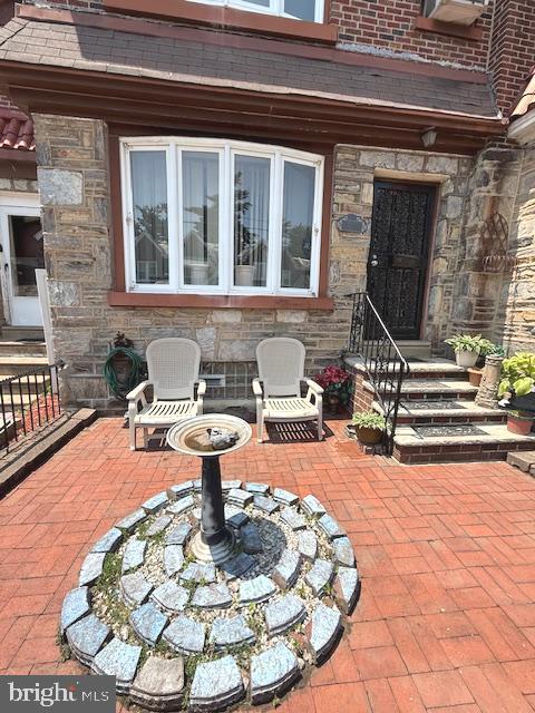 Come see this charming Stone and brick townhouse has lovely hardwood floors and a welcoming layout with three bedrooms, one full bath and one half bath. Initially you will be welcomed by the fenced paver terrace out front with garden features, hose and slate steps. Come through the brand new front door into a giant living room with space for entertaining, gleaming hardwood floors and can lights. From there enter into the spacious dining room graced with a chandelier and more hardwoods. The kitchen has a new gas stove, garden window , pendant lights and counter seating. Beautiful wood steps lead you upstairs to the huge main bedroom with a chandelier and 2 closets. In the hall is an updated 4 piece ceramic tile bathroom featuring a skylight, tub, stall shower, toilet and vanity.  Nice sized 2nd and 3rd bedrooms complete the second level that has hardwood floors as well. In the fully finished basement there is a laundry area with utility sink, large half bath with ceramic tile, double sinks and lots of cabinets. In addition to that there is a large family room with glass doors to a brick walled paver patio that has a locking door to the alley. Truly an oasis of privacy and peace. Roof replaced 2024. You do not want to miss this great move in ready home! Half of a block walk to Cheltenham Ave. providing easy access to public transportation.