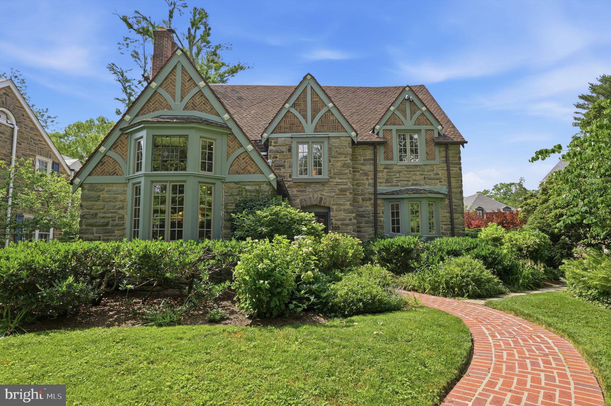 Welcome to this enchanting Mount Airy Tudor, where timeless craftsmanship meets thoughtful modern updates. Situated on a beautifully landscaped lot, this exceptional 5-bedroom, 3.5-bath home offers generous living spaces, architectural charm, and remarkable flexibility.

Distinctive features include a handmade tile gas fireplace, elegant industrial chandeliers, a cedar closet, and beautifully preserved character throughout. The inviting sun porch overlooks a deep, fully fenced backyard featuring manicured perennial gardens, a low-maintenance irrigation system, raised vegetable beds, and ample space for recreation and entertaining.

A first-floor au pair/in-law suite with an updated full bath and jetted tub provides ideal space for multigenerational living, guests, or a private home office. The main level also offers spacious living and dining rooms, a full pantry, a charming sunroom with a gas stove, and an oversized gourmet kitchen featuring leathered granite countertops and high-end black matte GE Monogram appliances.

Upstairs, the primary suite serves as a private retreat with a walk-in closet and a beautifully renovated spa-like bath. Additional highlights include fresh exterior paint, an attached garage equipped for EV charging, and exceptional outdoor living spaces. This one-of-a-kind home perfectly blends historic elegance with modern comfort and convenience.
