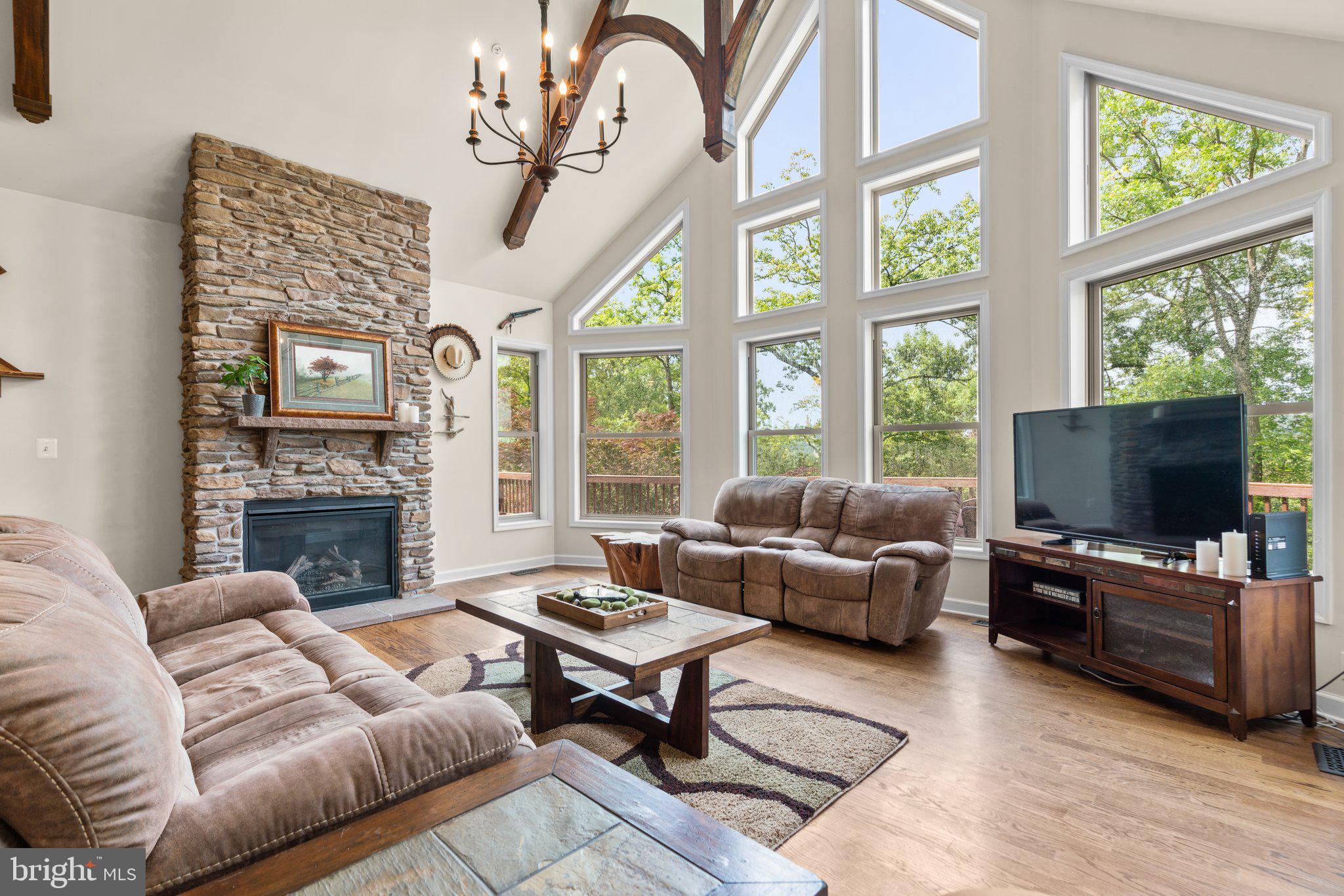 Welcome to your dream retreat! This stunning contemporary A-frame home in the picturesque Pinehurst Village of Lake Linganore features 4 spacious bedrooms and 2.5 bathrooms.  Featuring a distinctive reverse floor plan, the main living level showcases an inviting ambiance of wood beams and open living spaces. The expansive living area, with its vaulted ceilings and large windows, provides breathtaking seasonal views of Lake Linganore, bringing the serene beauty of nature right into your home.  The well-appointed kitchen is perfect for cooking up family meals, with ample counter space and cabinetry. Adjacent to the kitchen, the dining area offers a generously sized spot for gatherings, with easy access to the outdoor deck, spanning the full-length of the front of the house - perfect for summer barbecues or simply enjoying a quiet morning coffee. Retreat to the primary bedroom suite, featuring a private bathroom with a luxurious shower, plenty of closet space and private access to the expansive deck. On the entry level, you’ll find two of the four bedrooms, and a full bath.  Additionally, this level incorporates an additional living room with an oversized, electronic movie screen, projector and a gas fireplace, making it the ideal space for movie nights and gatherings.  Outside, the property offers a peaceful backyard with two patio areas, one with a built-in firepit. Located in the Lake Linganore community, you'll have access to a range of amenities, including private lakes, walking trails, and recreational facilities. Don't miss this opportunity to own a slice of paradise with seasonal lake views. Schedule your showing today and experience the perfect blend of modern comfort and natural beauty!