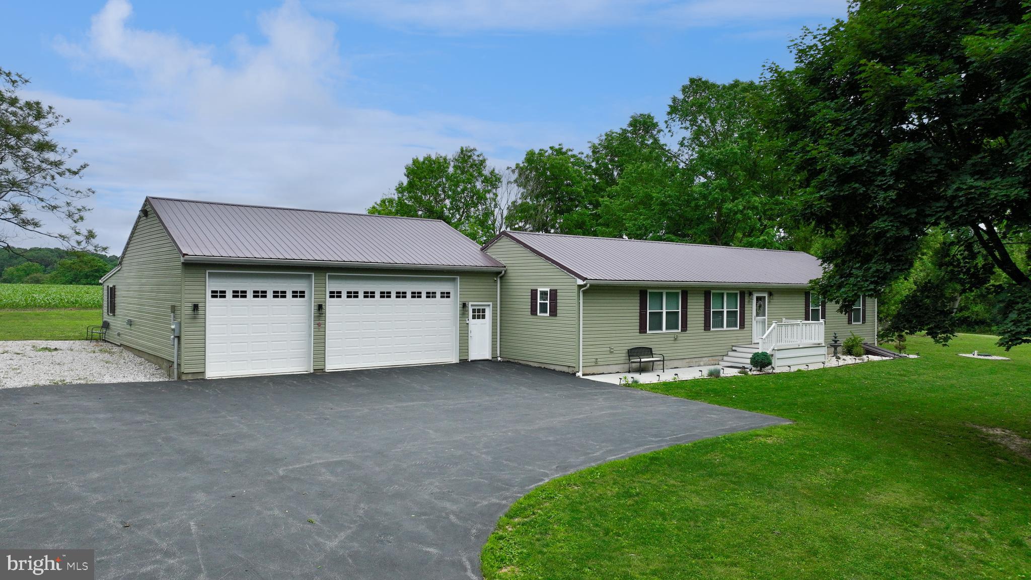 SIX-CAR GARAGE! Welcome to 1025 White Oak Rd, where privacy, quality craftsmanship, and modern comfort come together on over 2 scenic acres in Windsor Township. Recently appraised and competitively priced, this exceptional property offers an incredible opportunity to own a thoughtfully designed home with outstanding amenities. Built in 2017 and backing to more than 25 acres of open land, the property delivers a rare combination of space, efficiency, and peaceful country living.

Constructed with durability and energy efficiency in mind, the home features 2x12 floor joists, 2x6 exterior walls with foam insulation, and metal roofing on both the house and garages. Inside, you'll find an open-concept layout with luxury vinyl plank flooring, fresh paint, updated lighting, and thoughtful finishes throughout.

The inviting living room features an electric fireplace, built-in cabinetry, ceiling fans, and a mounted smart TV that conveys. The spacious kitchen is designed for everyday living and entertaining, offering 42" white cabinetry, granite countertops, tile backsplash, under-cabinet lighting, pull-out shelving, newer stainless-steel appliances, a large center island, and an oversized walk-in pantry.

A flexible room off the main living area can serve as a home office, guest room, or additional bedroom and provides direct access to the rear deck. The primary suite offers French doors with built-in blinds leading to the expansive composite deck, a large walk-in closet, and a private bath featuring a tiled walk-in shower. Two additional bedrooms provide comfortable accommodations, while the hall bath includes a Bluetooth-enabled fan with speaker and customizable lighting.

The well-equipped laundry room includes built-in cabinetry, folding space, washer, and dryer. The lower level offers a large finished flex space with luxury vinyl plank flooring, painted walls, excellent storage, Bilco door access, and a fire-resistant safe that will remain with the property.

Outdoor living is where this home truly shines. The nearly 1,200-square-foot composite deck is partially covered and wired for a mounted television, creating the perfect setting for entertaining or relaxing while enjoying the surrounding views. A covered patio, firepit area, and partially fenced yard provide additional outdoor enjoyment, with plenty of room for future additions such as a pool, volleyball court, or other recreational amenities.

Car enthusiasts, hobbyists, and anyone needing exceptional storage will appreciate the attached garage with capacity for up to six vehicles, complete with smart garage door openers, along with a separate rear three-bay garage/workshop. Additional features include security cameras with DVR, Govee smart exterior lighting, keyless entry, multiple exterior outlets and hose bibs, dedicated RV parking, and a 50-amp RV hookup.

Wildlife sightings, peaceful country views, and the property's exceptional combination of garages, upgrades, and outdoor living make this a truly unique offering. Move-in ready and available for a quick settlement. Schedule your private tour today and experience everything 1025 White Oak Rd has to offer.