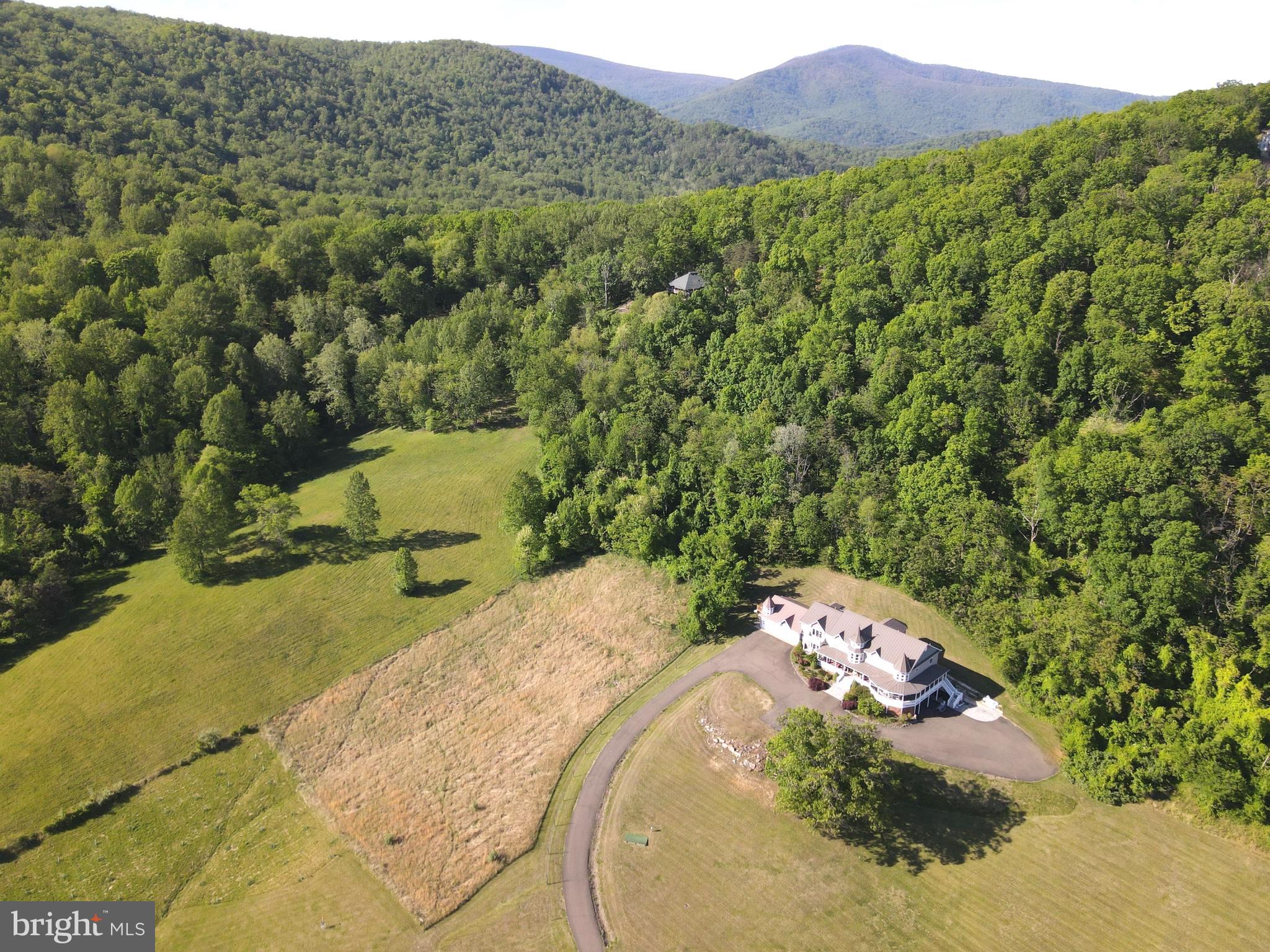 THE ROMANCE of an earlier era, LUXURIES of today and an EFFORTLESS sense of scale await on 29 acres with close by PANORAMIC VIEWS of the Blue Ridge Mountains, the surrounding embrace of the neighboring Shenandoah National Park in the day and the celestial Milky Way at night, all about an hour west of Washington DC.  This delightfully private estate feels less like a property and more like a hidden chapter.  Spectacularly spacious, delightfully livable and filled with ultimate comfort, this home  of roughly 9,600 sq ft unfolds with an effortless sense of scale, designed for living that stretches across generations.  *  Inside spaces are composed with intent.  Sunlit rooms invite slow mornings with coffee and books, fireside corners draw in conversation that lingers long past dusk.  A grand yet welcoming kitchen anchors the home, with generous dining and entertaining areas.  The family room becomes a heartbeat space, equally suited for family traditions, milestone toasts, and the easy chaos of everyone home at once.  A walkout level transforms into a spirited retreat of its own. A bar with kitchen sets the stage for evenings that drift between billiards, ping pong, the crescendo of a big game and laughter echoing just enough to remind you this house was built to be lived in, not tiptoed through.  ******  Six bedrooms are thoughtfully arranged to balance connection with privacy, including two separate private entrance apartments. One apartment attached to the garage offers an ideal two story escape where younger generations can carve out their own world within the larger frame.  The other apartment provides refined independence for your boomers who want to go to bed early and appreciate their own serene retreat.  * Think retirement. Think nature. Think work at home, for this office is more productive than any city office can possibly be. Think easy commute when you must go to town and a multi-generational home if so inclined.  This is not simply a home. It is a place where generations gather, scatter, and return again, each time adding another layer to its story.