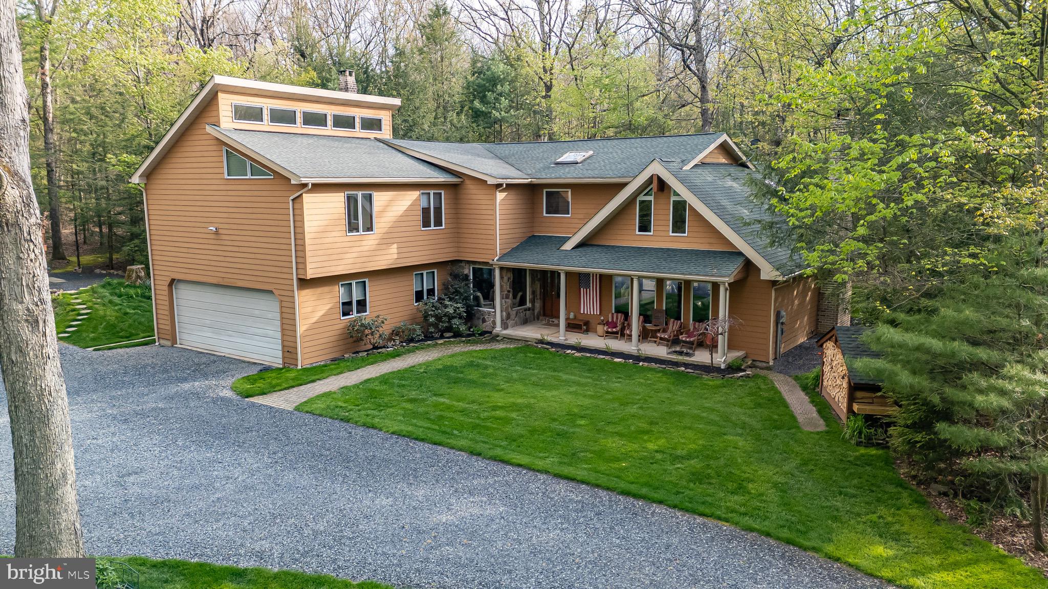 Set on 6.17 pristine acres in Kunkletown, this striking contemporary home offers the perfect blend of privacy, space, and natural beauty. With 3,572 sq ft, this 4-bedroom, 2.5-bath retreat features a dramatic wall of windows that floods the home with natural light and brings the outdoors in. The main living area is anchored by a stunning floor-to-ceiling stone, wood-burning fireplace and a stone-faced bar area--perfect for cozy nights and entertaining. Upstairs are 4 spacious bedrooms and a spacious loft overlooking the living room, perfect for an office/studio or recreation room. The Primary bedroom and bath offers vaulted ceilings.  The yard is a private oasis complete with a deck, patio and hot tub - the beautiful landscape includes flowering trees, perennials and there is plenty of room for a garden!
The home has been thoughtfully updated, including the kitchen with center island, primary bath, HVAC, and a 10 year old roof. An attached 2 car and detached 2-car heated garages with finished loft/office space adding flexibility for work, hobbies.  The charming stone bothy was custom built and in view from the front porch! Chicken coop included! Enjoy easy access to over 11,000 acres of outdoor recreation, with walking/hiking trails, hunting, bird watching and more...just minutes away at Penn Forest/Wild Creek Reservoirs and boating/fishing/kayaking/picnicking at Beltzville State Park. Jim Thorpe for dining/shopping, biking on the D&L trail, Close to skiing, wineries, restaurants. -  Live like you're on vacation everyday!