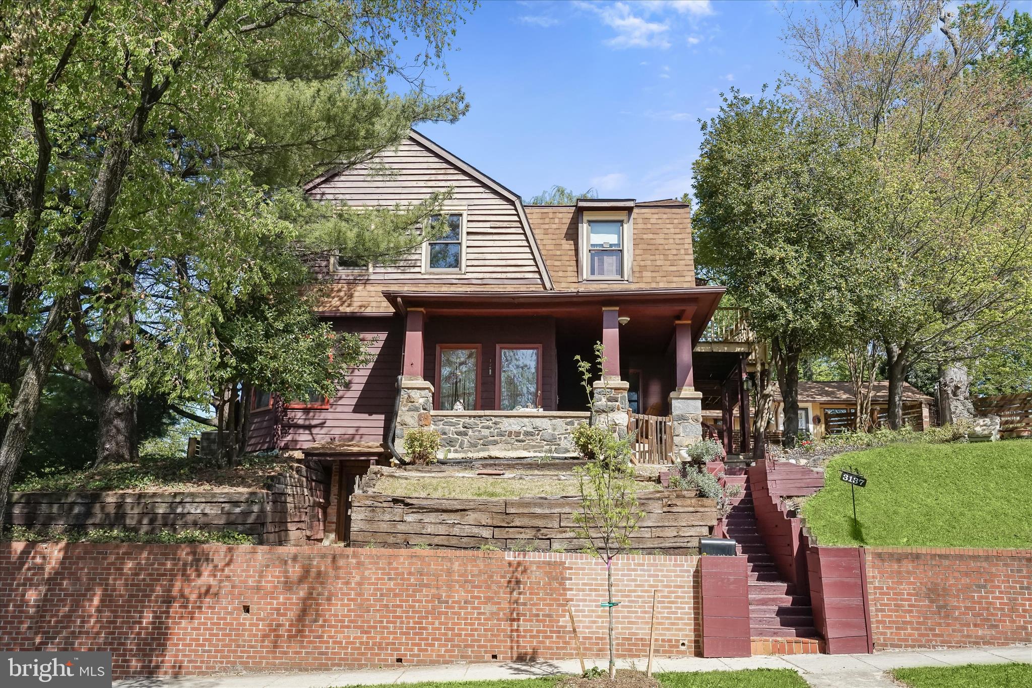 Nestled in the sought-after Woodbridge/Brookland community, this exquisite residence offers a rare blend of architectural elegance, modern amenities, and serene outdoor spaces. From the moment you arrive, the meticulously landscaped grounds and sophisticated curb appeal set the tone for the grandeur within.  Step inside the main level and be greeted by rich hardwood floors, intricate architectural details, and a flood of natural light pouring through large windows adorned with plantation shutters. The formal dining room flows effortlessly into the gourmet kitchen, where a stone-surround gas fireplace, picture window with garden views, and recessed lighting create an inviting ambiance for entertaining.  The kitchen is a chef’s dream, featuring a central island with breakfast bar, stainless steel appliances, double sink, glass tile backsplash, ceramic tile flooring, ample cabinetry, and not one but two casual dining areas or sitting areas—perfect for intimate mornings and peaceful evenings.  The living room, also boasting a stone-surround gas fireplace, offers exposed wood beams and direct access to the rear patio—ideal for relaxing or hosting guests in style.  Upstairs, the luxurious primary suite is a true retreat, complete with a spacious sitting area, a vaulted ceiling, access to a private balcony, exposed beams, a skylight, and a spa-inspired en suite bath featuring double vanities and a walk-in, sauna-style shower. Two additional bedrooms and a beautifully appointed hall bath with a jetted soaking tub complete the upper level.  The fully finished lower level offers exceptional flexibility. It features its own kitchen, bath, laundry, and potential for two additional bedrooms. With a private entrance, it’s perfect for guests, extended family, or an income-generating rental.  Completing this extraordinary property is a charming detached carriage house, thoughtfully converted into a studio with a full kitchen, bath, cathedral ceilings with exposed beams, skylight, ceramic tile flooring, and a cozy front porch—ideal for a guest suite, rental, or creative space.  Conveniently located near major commuter routes, including US-1, US-50, and I-695, this exceptional home offers upscale city living with space, privacy, and timeless elegance.