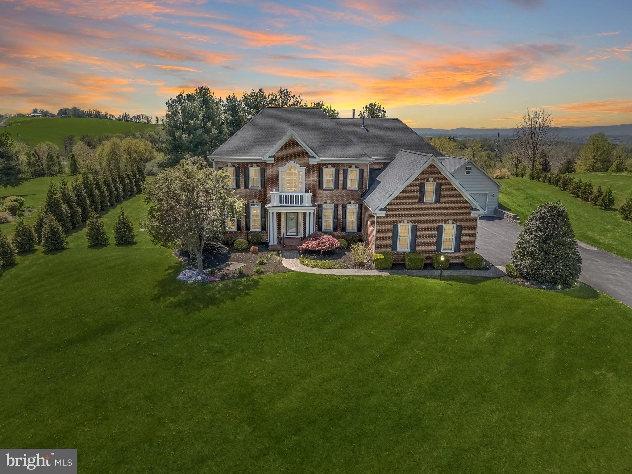 Welcome to 4209 Maryland Court, a stunning retreat nestled in the hills of the Middletown Valley, offering breathtaking views of Maryland National Golf Course and the Catoctin Mountains. Set on a beautifully landscaped 3.15-acre lot, this exceptional residence blends timeless elegance with thoughtful modern upgrades, creating a serene and private setting. Inside, architectural details shine in every room, from gleaming hardwood floors and stately columns to classic moldings and sun-drenched interiors. A grand two-story foyer welcomes you with formal living and dining rooms on either side, setting the tone for the home’s refined design.
The heart of the home is the thoughtfully designed chefs eat-in kitchen, featuring a suite of premium appliances including a Monogram cooktop with range hood and a recently installed Thermador built-in refrigerator, along with granite countertops, a center island with breakfast bar, a planning station, and a walk-in pantry. A complete water filtration system, including a reverse osmosis drinking water system, adds both convenience and peace of mind. The adjoining morning room is filled with natural light from a wall of windows and provides access to the spectacular outdoor living space, complete with a custom patio, hot tub, and outdoor shower station perfect for entertaining or relaxing. The spacious family room is anchored by a cozy fireplace and built-in shelving, while a private office with French doors and a bay window offers the ideal work-from-home space. A mudroom, two powder rooms, and access to the attached garage complete the main level.
Upstairs, the luxurious primary suite serves as a private retreat, featuring a tray ceiling, expansive sitting room with fireplace, two walk-in closets, and a spa-like bath with separate  vanities, soaking tub, water closet, and glass enclosed shower. Three additional bedrooms provide ample accommodations, including one with an en-suite bath and two connected by a Jack-and-Jill bath, along with a convenient upper-level laundry room.
The finished lower level expands the living space with an expansive game room, a media room with wet bar, granite countertops, and wine fridge, an exercise room, a bonus room, and abundant storage.
Additional highlights include Wi-Fi enabled motorized fabric blinds throughout entire first floor and primary bedroom, a three-zone HVAC system for enhanced comfort and efficiency, built-in whole-house surge suppression, an attached oversized three-car garage, and a detached two-story garage equipped with heating and air via mini-splits. The detached garage also features its own 100-amp electrical service, offering excellent flexibility for a workshop, studio, or hobby space, along with an upper-level bonus area ideal for an office or creative retreat. With an extensive list of updates and an unparalleled setting, this remarkable home offers the perfect balance of luxury, comfort, and scenic beauty. Roof was replaced in 2020.