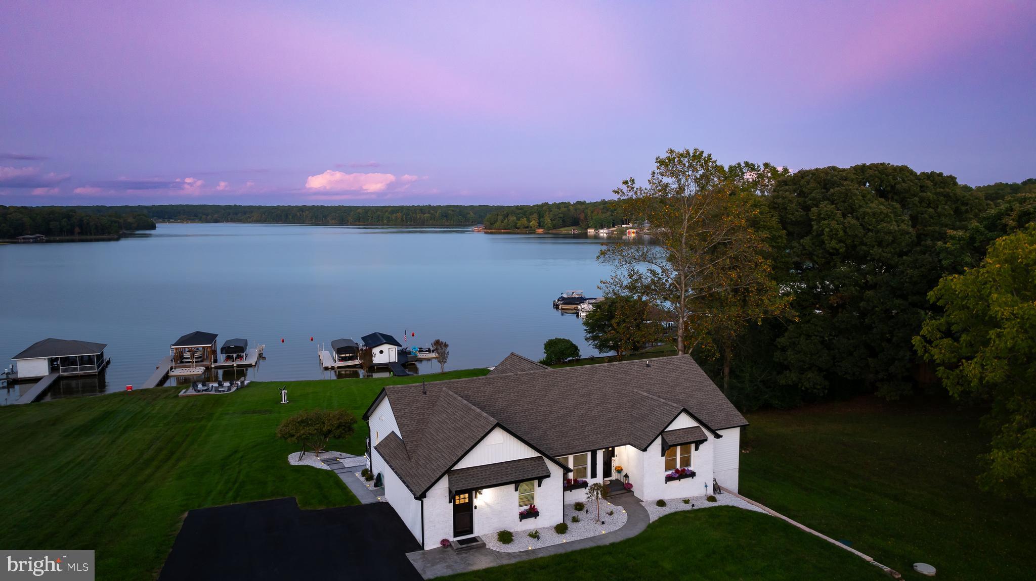 A stunning waterfront retreat with huge unobstructed water views on the public side of Lake Anna, Virginia.  Experience unparalleled luxury in this captivating lakefront home that was recently renovated, inside and out, all thoughtfully designed to showcase the finest finishes.  Nestled on 1.39 acres of beautifully manicured grounds, this exclusive retreat offers breathtaking panoramic water views, impeccable design, and resort-style amenities that redefine luxury living.  Step inside to discover over 4,000 square feet, 6 bedrooms, 3 full baths and an open floor plan perfect for entertaining your family and friends.  The family room features soaring shiplap ceilings, a large gas fireplace, and sliding doors to the outdoor covered deck that overlooks the water.  The gourmet kitchen is a showstopper with its massive center island that has seating on three sides, high-end stainless steel appliances, sleek granite countertops offer tons of counter-space, 6 burner gas stovetop, under-mount farmhouse sink, and a walk-in pantry with wood shelving and a custom barn door.  It flows seamlessly into the inviting family room and the dining area, making it the perfect space for entertaining.  Wake up to breathtaking lake views from the luxurious owner’s suite that has a large walk-in tile shower with dual rain shower heads, a soaking tub, dual vanities, and a large walk-in closet with a center island.  There is one additional bedroom, full bath, laundry room and a mud room on the main level.  The finished walkout basement  provides extra living space with a family room, kitchen, 4 bedrooms, a full bath, man cave and a storage room with laundry.  Outdoor living spaces are equally impressive, with a large composite deck with waterproofing below, covered porch and concrete patio.  Take a stroll down to the water's edge to 150 feet of pristine rip-rap shoreline, your own sandy beach, floating boat dock, covered sun deck, storage room, and a double jet ski pad.  Gather around the lakeside fire pit to roast s'mores or enjoy a cocktail as the evening unwinds.  All new windows and doors, whole house water treatment system, paved driveway and two storage sheds (one with electric).  Just bring your family, friends, and swimsuit and start making your memories here.  Don't miss this incredibly rare opportunity to own a waterfront home in a great location with unbeatable views!  Less than two minutes to groceries, dining, ABC store, and much more.  Come experience for yourself this truly remarkable, one-of-a-kind property.  Short term rentals are permitted in Oak Grove Estates.  Too many improvements and upgrades to list here!  See MLS documents for full list of improvements and items that can be purchased separately.