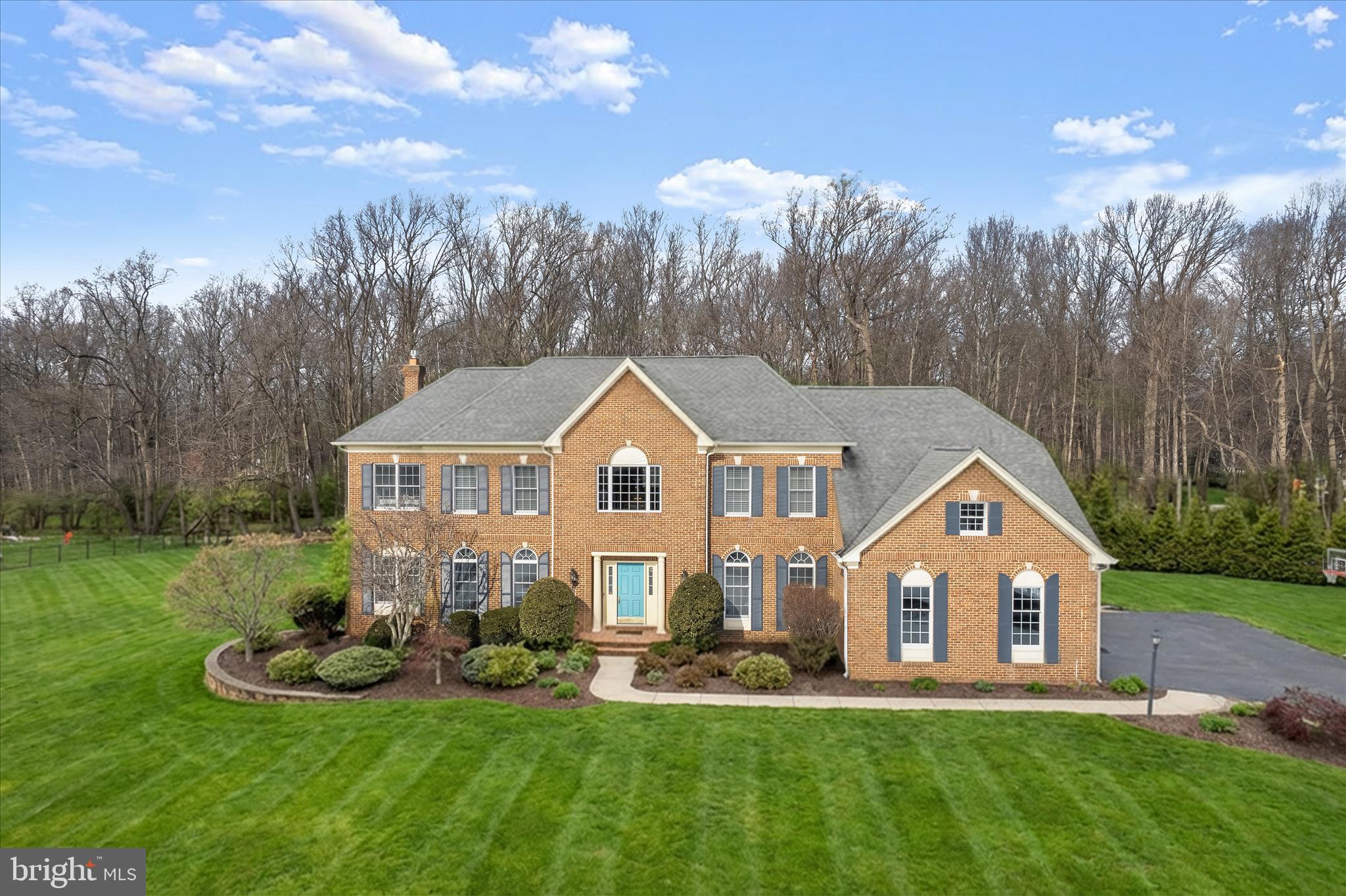 Set within the sought-after River Hill High School District in the Pindell Chase community, this stately Toll Brothers Edgebrook model is gracefully positioned on over an acre of meticulously designed landscaping and hardscape. Curated outdoor living blends seamlessly with the surrounding natural setting and huge, flat side yard to create an atmosphere of refined luxury. The classic brick exterior and walkway introduces an elegant, pristine interior, beginning with a soaring two-story foyer richly detailed with chair railing, box wainscoting, picture molding, and crown molding. Flanking the foyer, the formal living and dining rooms exude timeless sophistication, accented by classic crown molding and chair railings. The dining room is further enhanced by box wainscoting and a tray ceiling, offering an ideal backdrop for gourmet dining and special occasions. French doors open to a private main-level study with access to the inviting family room. Here, high ceilings, plush carpet, and a gas fireplace with a brick surround create a warm yet elevated gathering space. The family room flows seamlessly into the thoughtfully designed gourmet kitchen featuring stainless steel appliances, granite countertops, decorative backsplash, a center island with a breakfast bar and sink, and 42-inch cabinetry with pull-out drawers. A butler’s pantry and sunlit breakfast area enhance the home’s inviting flow. The adjoining sunroom serves as a tranquil retreat highlighted by hardwood floors, skylights, and direct access to the expansive 2-level brick paver patio and outdoor fireplace, all while offering serene views of the surrounding landscape. The primary suite is a true showpiece, introduced through French doors delivers plush carpeting, crown molding, and a tray ceiling framing the space, complemented by a sitting room, walk-in closet with built-in organizers, and a double-sided gas fireplace. The spa-inspired primary bath features separate vanities, a dressing table, a jetted soaking tub, and a ceramic tile walk-in shower. Three additional generously sized bedrooms, two with walk-in closets, and two full baths complete the upper-level sleeping quarters. The fully finished lower level expands the living space with a media room featuring a projector wall, a game area ideal for billiards or table tennis, a playroom or potential guest suite, and a full bath. Ceramic tile flooring, chair railing, and box wainscoting add refined architectural detail, with direct access to the backyard enhancing functionality. Recent updates include: hot water heater (2024), insulated Hi-lift garage doors (2023), whole-house water filtration, 2 Tesla outlets, outdoor cameras, newer microwave, oven, dishwasher, designer range hood, disposal, sump pump and exterior lighting.  Ideally located near MD-32, US-29, and I-95, this exceptional residence offers convenient access to Baltimore, Washington, D.C., Maple Lawn, Clarksville, Merriweather Post Pavilion, and Patapsco State Park, delivering luxury living with unmatched connectivity and lifestyle appeal.