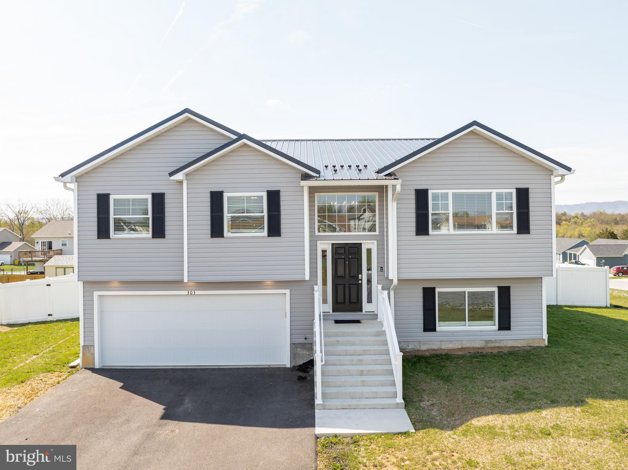 MULTIPLE OFFERS - Best and final due Saturday, April 26th, by 6:00PM. Welcome to this stunning custom-built split-foyer home, less than two years old and packed with upgrades throughout. Tucked away at the end of a quiet street on a spacious corner lot, this property offers privacy and charm with a sleek white vinyl fence and a striking black metal roof that perfectly complements the light gray vinyl siding. As you enter, you are greeted by a dramatic oversized window and stylish chandelier that set the tone for the modern finishes found throughout. The entire home features luxury vinyl plank flooring, recessed lighting, and ceiling fans for year-round comfort. The expansive main living area is anything but ordinary, with a bright, open-concept layout that flows seamlessly into the dining area and kitchen. The kitchen is a chef’s dream, complete with granite countertops, a peninsula perfect for casual dining, white cabinetry, stainless steel appliances, a single-basin stainless steel sink, and a large walk-in pantry. The primary suite is a true retreat, featuring tray ceilings, two walk-in closets, and private access to a massive back deck that spans the length of the home—ideal for morning coffee or evening relaxation. The en-suite bathroom offers a spa-like experience with a soaking tub, walk-in shower with built-in seating, and a private water closet. Downstairs, you will find a spacious additional bedroom with oversized closets, a third full bathroom, and a large recreation room that opens to a covered patio—perfect for entertaining or creating a cozy second living space. The laundry room is as stylish as it is functional, boasting granite countertops and ample cabinetry. Additional features include generous hallway storage, upgraded doors and closets throughout, and a 500+ square foot garage with extra space for storage and direct access to the backyard. Every detail of this home has been thoughtfully designed for comfort, style, and practicality. Do not miss your opportunity to own this one-of-a-kind property!