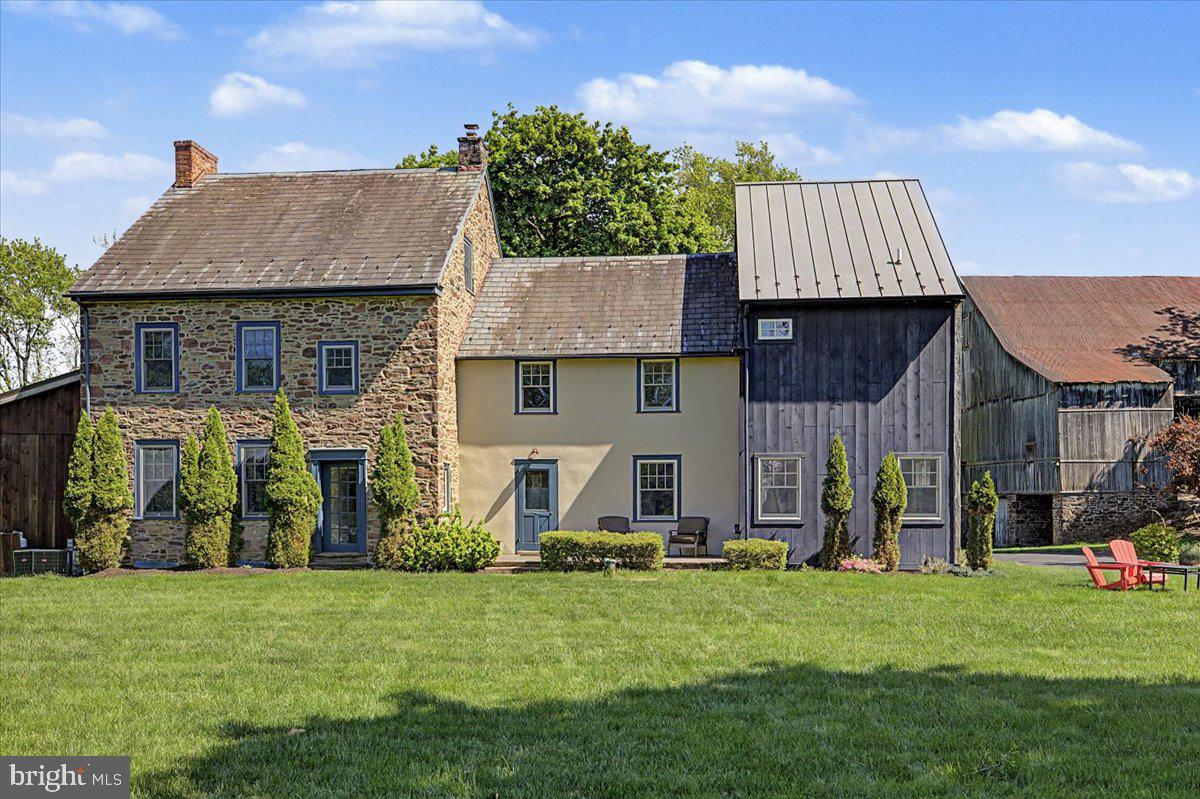 A rare Bucks County offering where timeless heritage meets modern country living. Set on nearly three picturesque acres, this exceptional historic farmhouse—originally built circa 1770 and thoughtfully expanded through 2019—blends the romance of a classic Pennsylvania stone home with the comfort and functionality of modern living. Offering approximately 4,000 square feet with six bedrooms and three-and-a-half baths, the property provides a refined sense of privacy just minutes from Doylestown, parks, and everyday conveniences.
Original architectural details including wide-plank floors, deep windowsills, and decorative fireplaces are beautifully paired with purposeful updates throughout. At the heart of the home is a custom Canaan Cabinetry kitchen with soapstone countertops and Miele appliances, designed for both everyday living and entertaining.
The outdoor spaces are equally compelling. A rustic covered porch overlooks the saltwater pool, while expansive grounds feature a basketball half-court, zip line, garden, and open lawn areas ideal for recreation, gatherings, or simply enjoying the surrounding landscape. A historic bank barn adds character and future potential, creating a setting that feels both timeless and inviting.
Located in Bucks County with convenient access to Doylestown, parks, trails, schools, shopping, and dining, the property offers a unique blend of privacy, open space, and accessibility. A truly distinctive estate where history, land, and modern living come together beautifully.