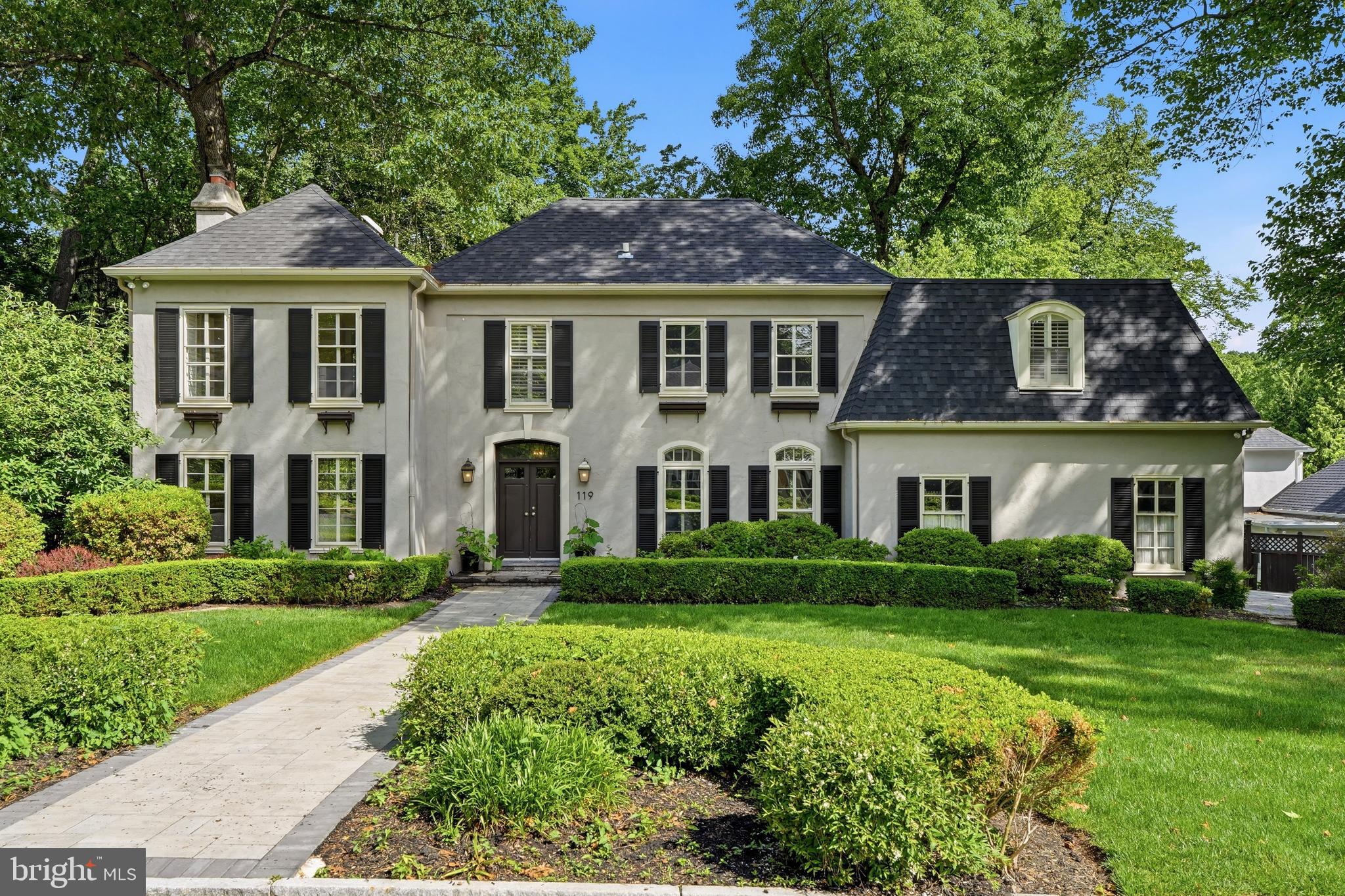 Welcome to 119 Woods Lane, a classic Main Line residence set within The Woods, one of Radnor Township’s most desirable and established neighborhoods. Framed by manicured landscaping and timeless curb appeal, this 4-bedroom, 4.5-bath home offers generous living space, beautiful natural light, geothermal heating and cooling, and a private setting surrounded by mature trees.  Enjoy the feel of a tucked-away neighborhood just minutes from Wayne, Radnor, major commuter routes, shopping, dining, and award-winning Radnor schools. A gracious foyer introduces the home’s warm hardwood floors, arched openings, and traditional flow, with a large living room featuring a fireplace on one side and a formal dining room with exposed brick detail on the other. The rear of the home is designed for everyday living, with a dramatic family room featuring soaring ceilings, tall windows, a brick fireplace, and direct connection to the breakfast area and kitchen. The bright white kitchen includes stone countertops, subway tile backsplash, stainless steel appliances, a large sink overlooking the trees, and a breakfast bar that opens naturally to the breakfast nook. Multiple rear-facing windows and doors create a strong connection to the recently refreshed oversized deck, fenced yard, and leafy surroundings. Upstairs, the spacious primary suite includes vaulted ceilings, wooded views, a large custom walk-in closet, and a private bath with soaking tub, walk-in shower, and double vanity. Three additional bedrooms, two full baths, and a flexible office/loft area overlooking the family room complete the second floor. The finished lower level adds valuable bonus space for recreation, work, fitness, guests, or play, along with a full bath and additional storage/utility space. A main-level laundry room, powder room, two-car garage, spiral stair to the yard, and peaceful fenced rear grounds add to the home’s everyday convenience. With classic character, flexible living spaces, and a prime location in The Woods, 119 Woods Lane offers a rare opportunity in the heart of Radnor Township.